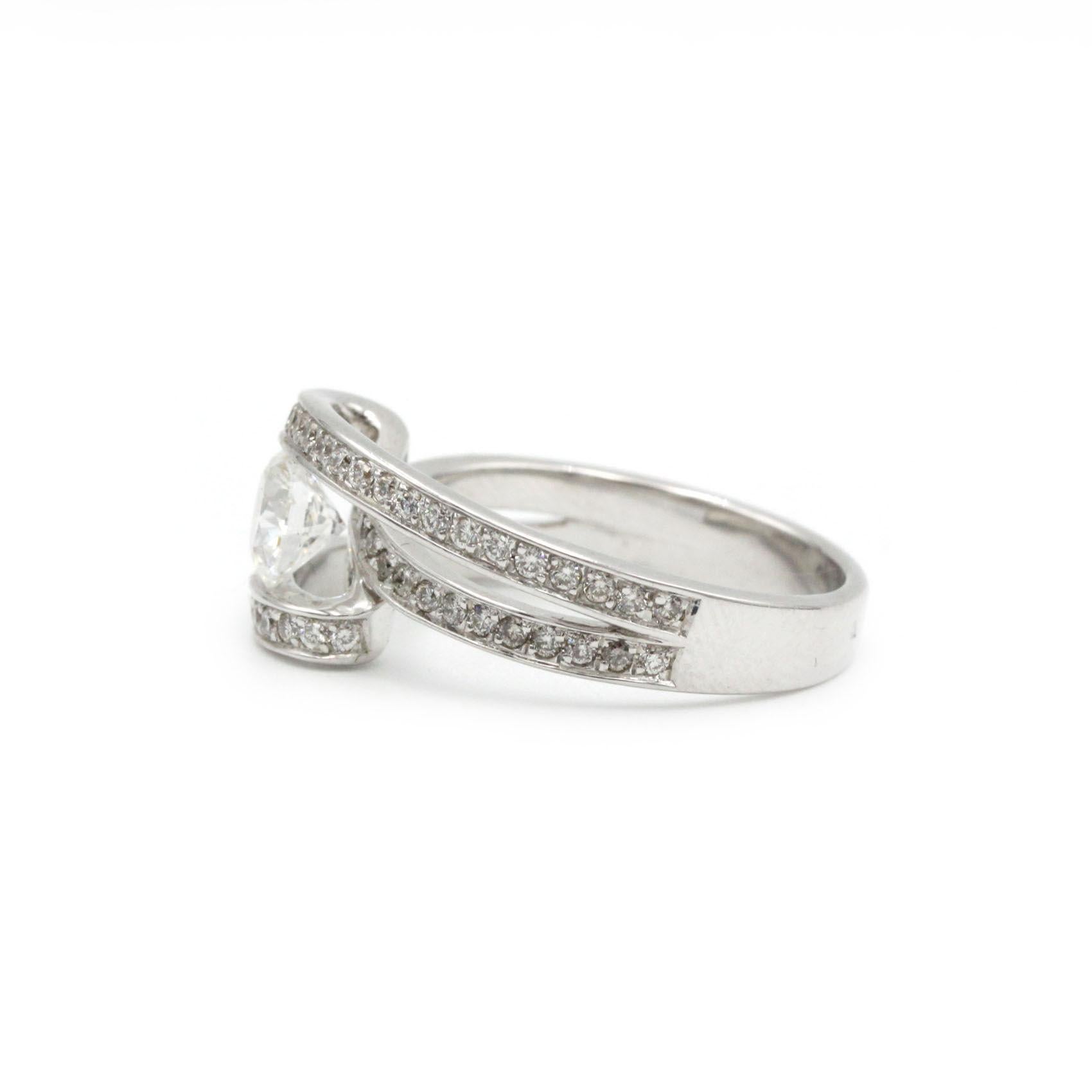 Este exquisito anillo de oro blanco de 18 quilates tiene en su centro un diamante redondo facetado de 0,70 quilates, color D y clase VVS, que deslumbra sobre una banda ancha engastada con aproximadamente 1 quilate de brillantes diamantes en pavé. La