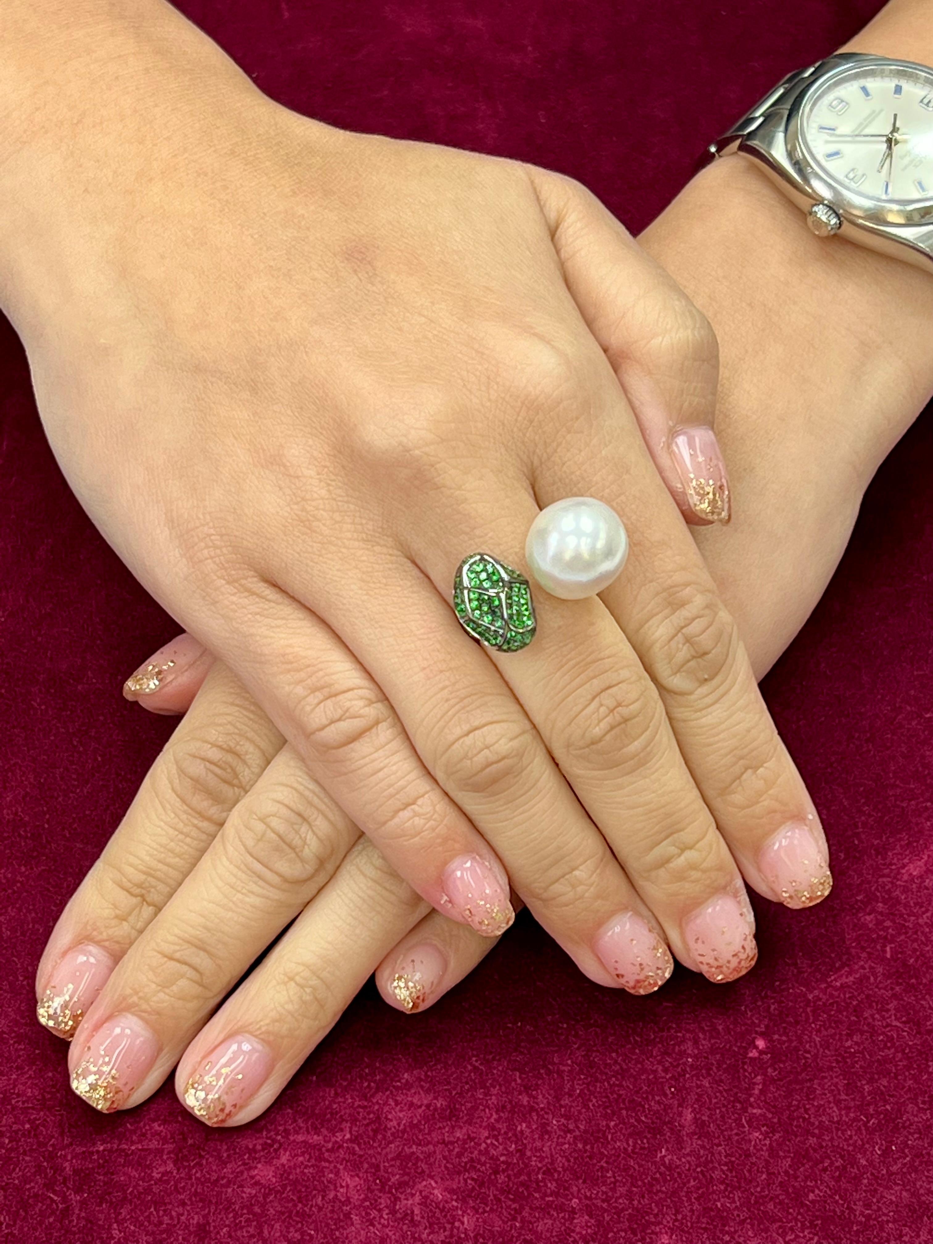 Please check out the HD video. This is a special South Sea pearl and Tsavorite cocktail ring. The center south sea pearl is 13.8 - 14.4 mm. This high quality pearl is almost round, has nice skin and high luster. The color is silver white. The ring