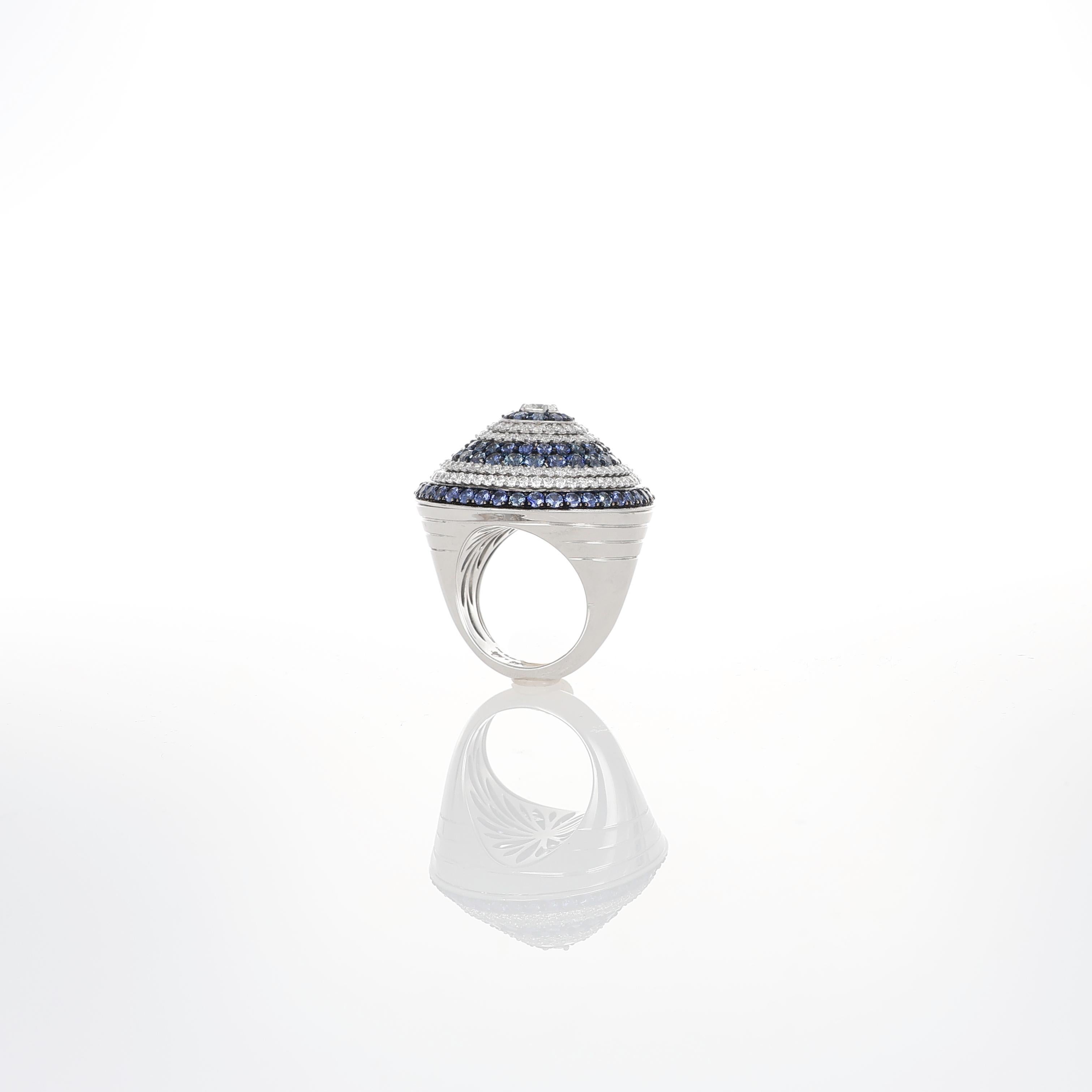 A striking and sculptural design, this 18K white gold ring is inspired by the dynamic form of a spinning top. The domed structure is meticulously set with 4.50 carats of round-cut blue sapphires and 2.15 carats of brilliant-cut diamonds, arranged in