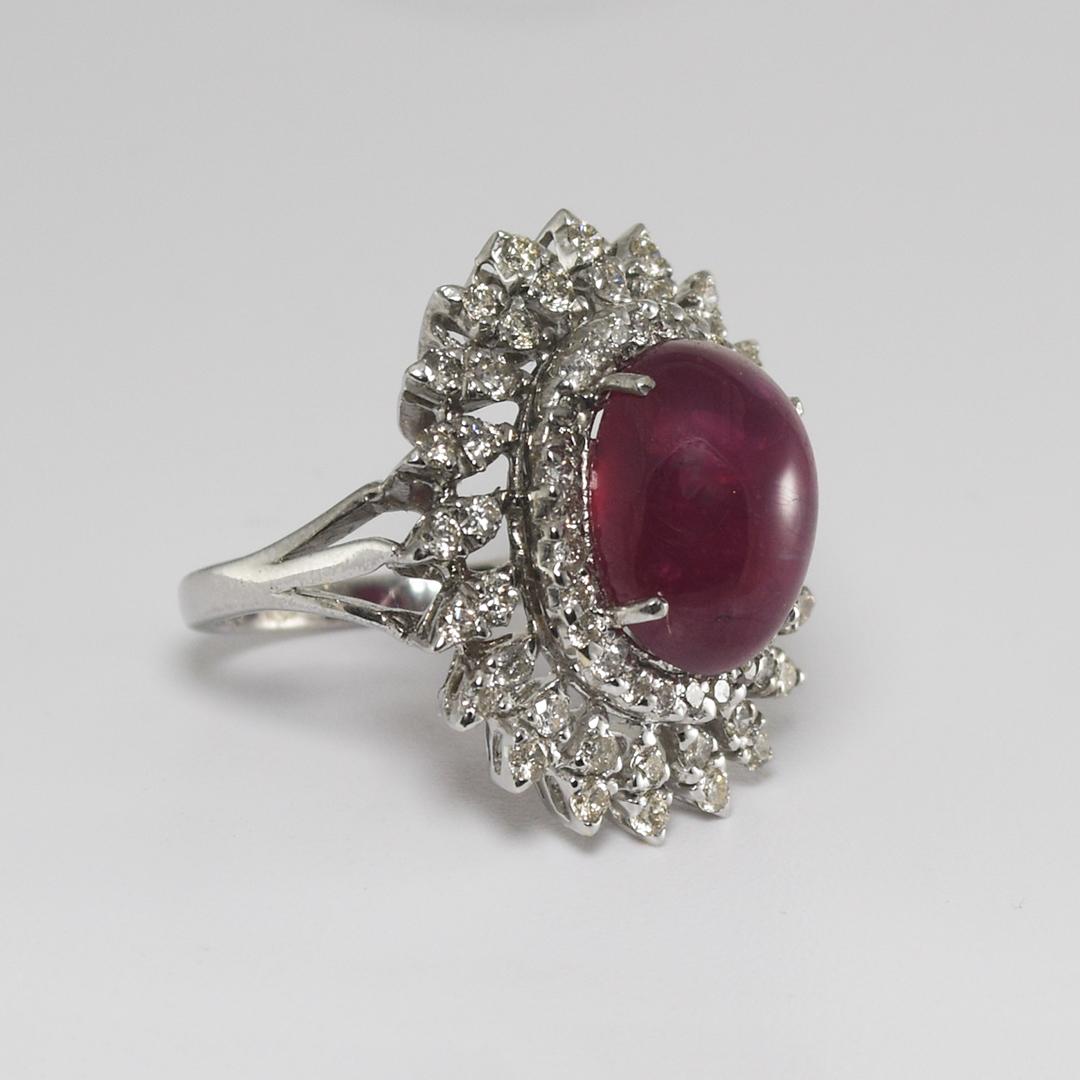 An incredible 18k white gold ladies' ring weighing 11.3 grams.
It has a large, deep red, lab-created cabochon ruby.
The lab-created ruby is surrounded by 1 carat of small round diamonds.
Beautiful mounting and craftsmanship.
Size 7.5.