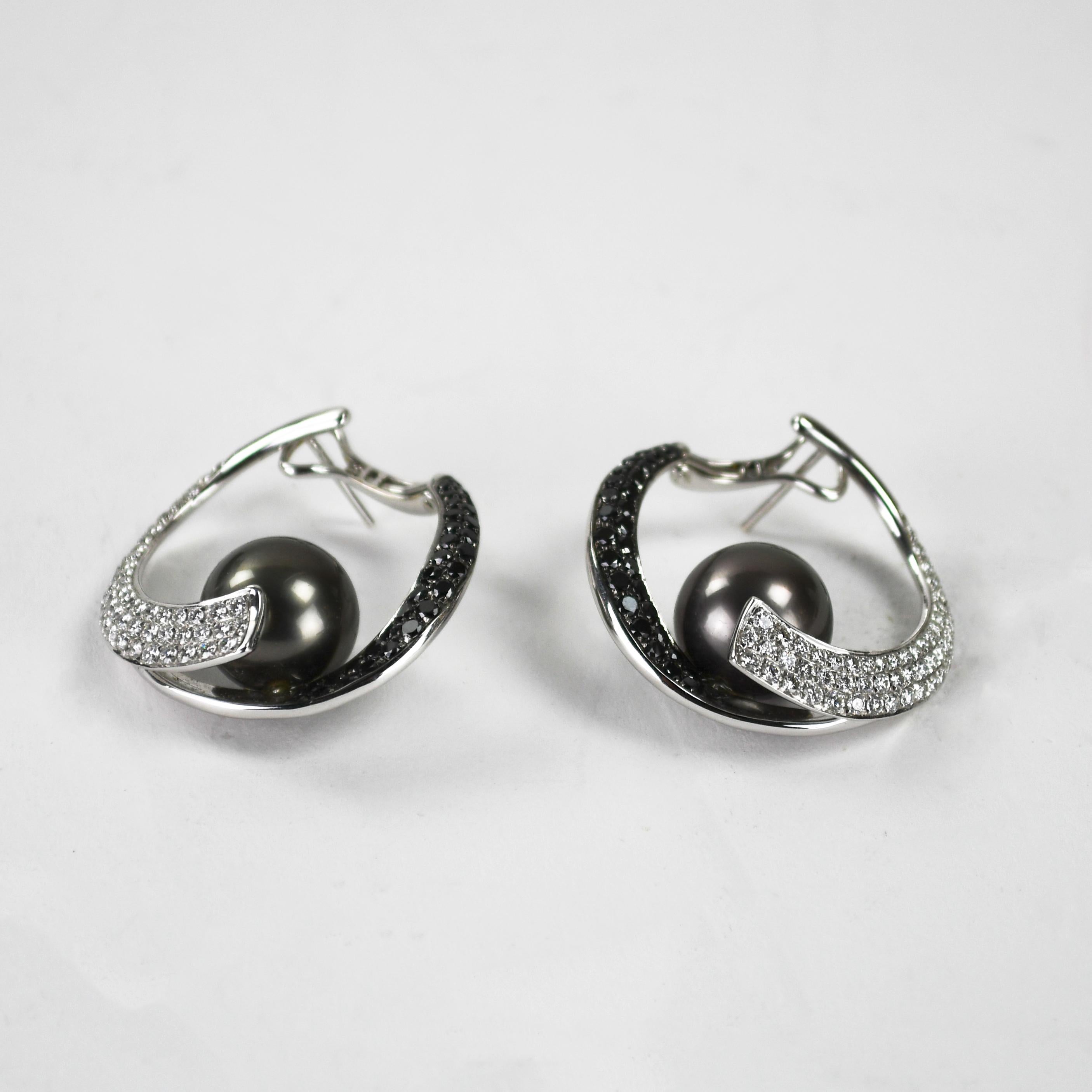 Orecchini su misura in oro bianco 18k, perle di Tahiti e diamanti.
Timbrato 750 18k e peso lordo di 15,3 grammi.
Le perle sono delle Tahiti nere di 11,5 mm, con un'ottima lucentezza e superficie.
I diamanti sono tagli tondi brillanti, 1,00 carati