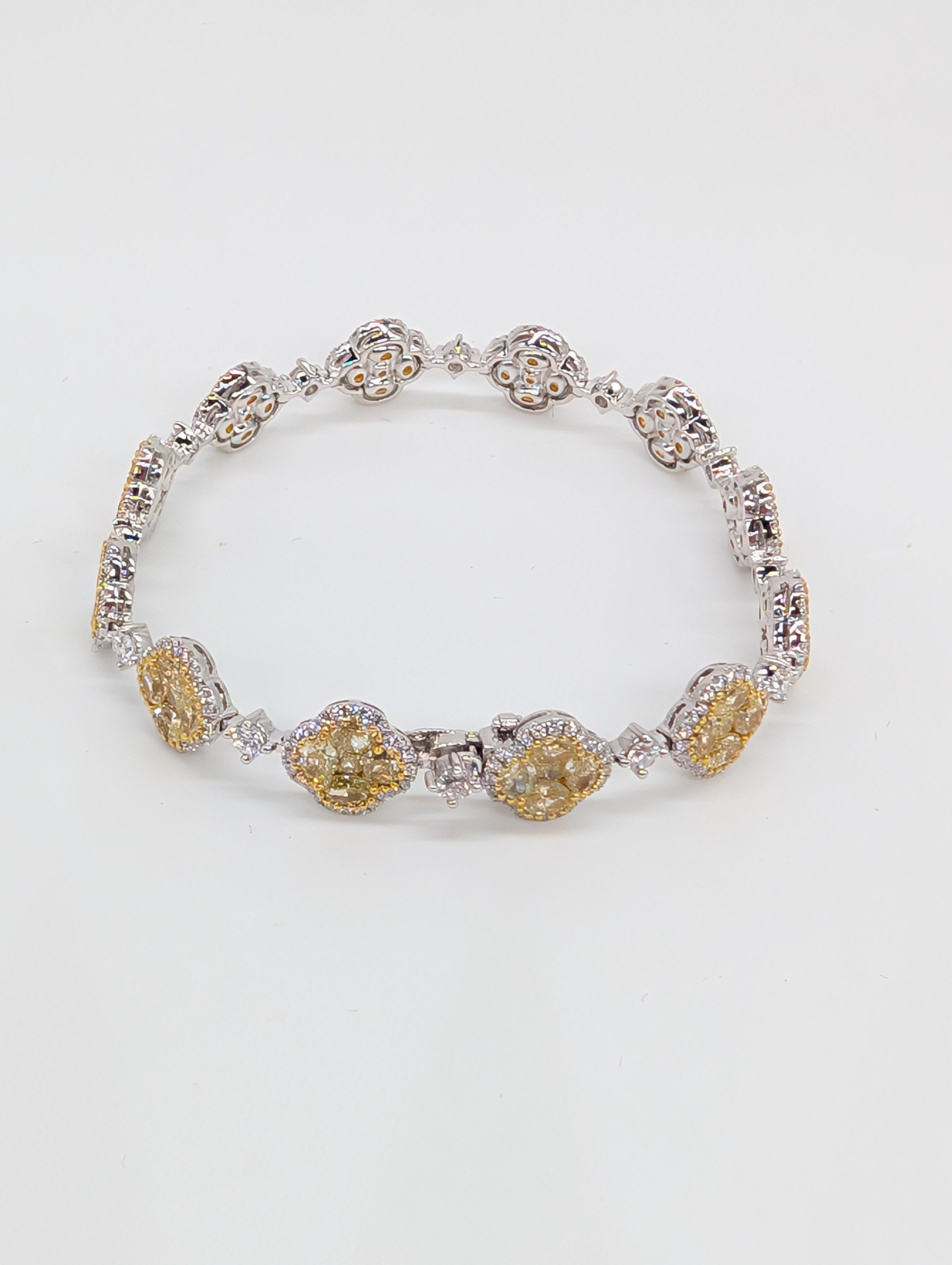 Dieses atemberaubende Tennisarmband aus 18-karätigem Weißgold ist ein echter Hingucker mit einer Reihe von gelben, oval geschliffenen Diamanten, die von einem strahlend weißen, rund geschliffenen Diamantring umgeben sind. Die auffälligen gelben