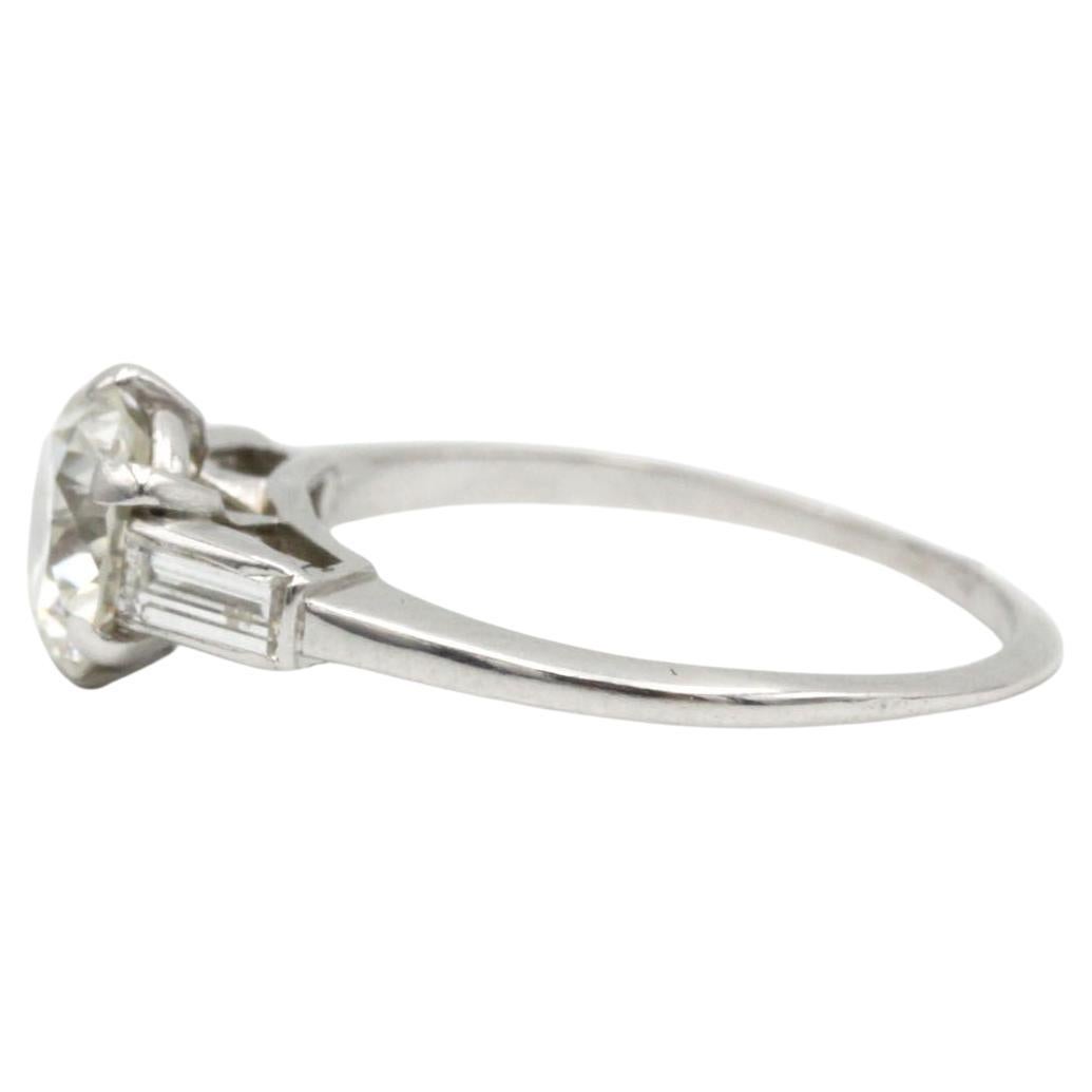 Realizzato in oro bianco 18 carati, questo anello a tre pietre di ispirazione vintage presenta al centro un affascinante diamante di 1,30 carati dal taglio antico. Affiancato da due accenti a gradini affusolati (circa 0,35 carati in totale), il