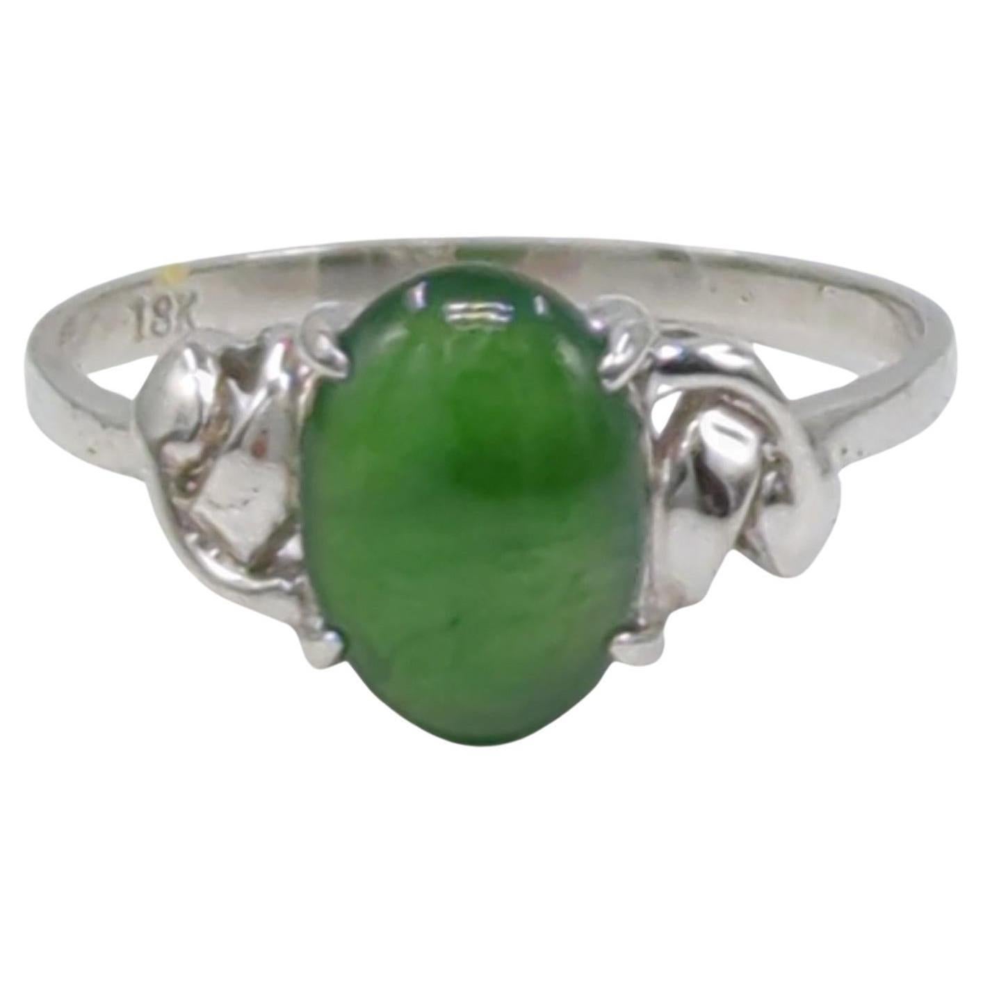 This simple yet elegant ladies' ring is crafted in 18K white gold and weighing 1.5 grams. At the center of its design lies a captivating oval cabochon deep green A grade jadeite, The jadeite is translucent and exhibits a high-quality polish, making