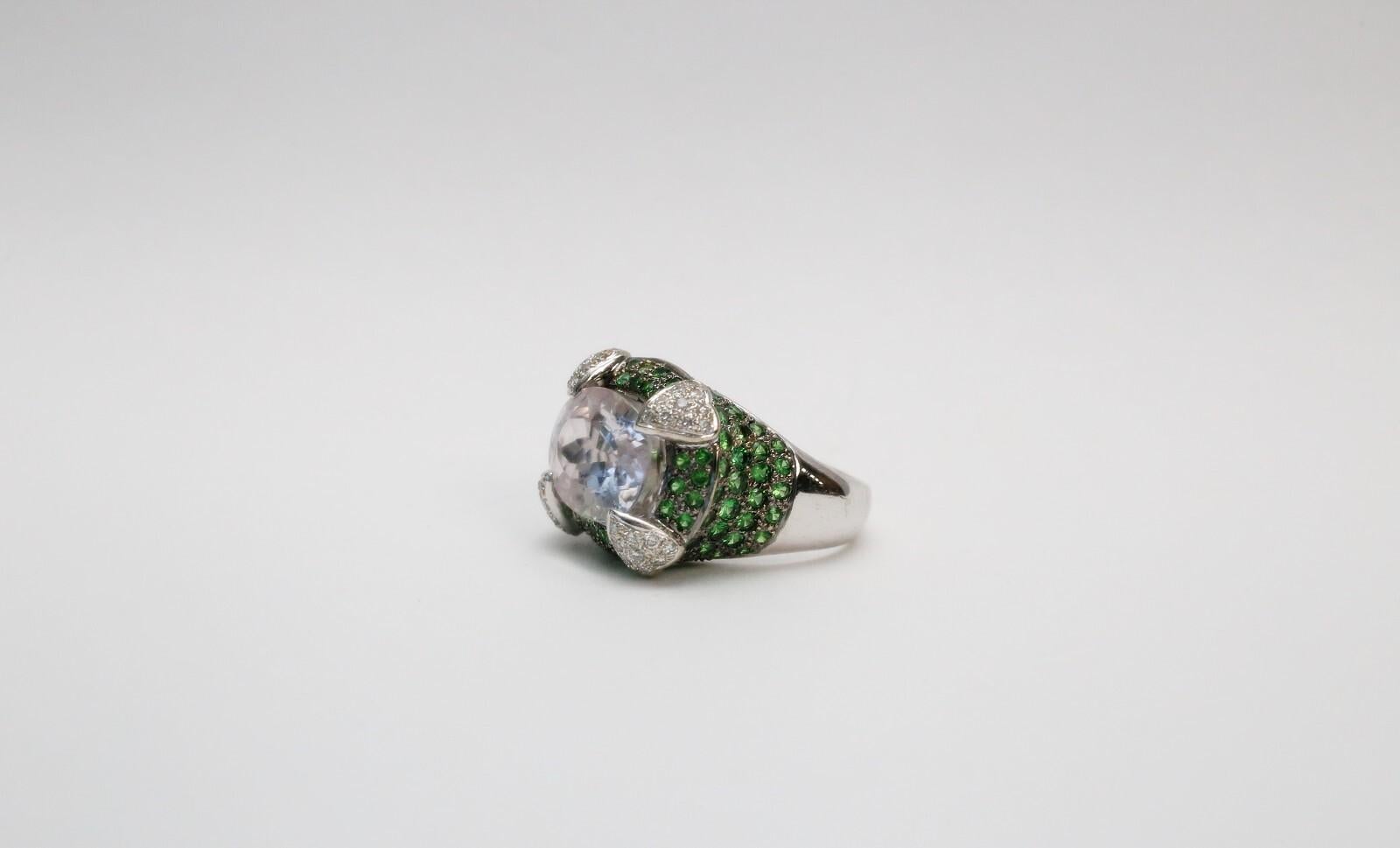 Dieser auffällige Ring aus 18 Karat Weißgold besticht durch sein kühnes und elegantes Design, in dessen Mittelpunkt ein Kunzit im Ovalschliff steht, der für seinen zarten rosa-lavendelfarbenen Farbton bekannt ist. Das Herzstück wird durch vier
