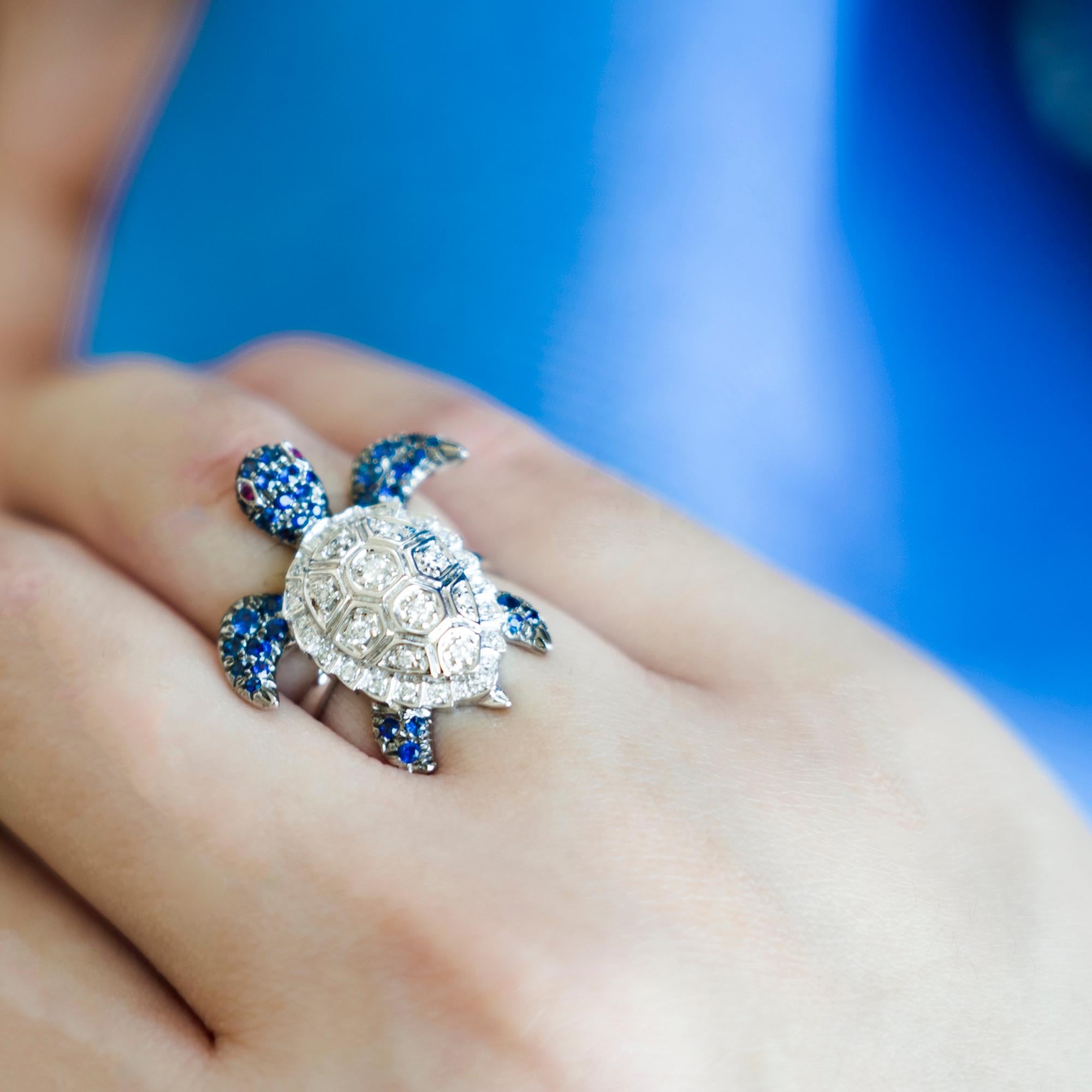 18K White Gold Turtle Blue Sapphire and Diamond Ring

42 Blue Sapphires - 0.63 CT
38 Diamonds - 0.26 CT
2 Rubies - 0.02 CT
18K White Gold - 6.48 GM

Turtle represents intuitive development, protection, wisdom, patience, and determination. As a