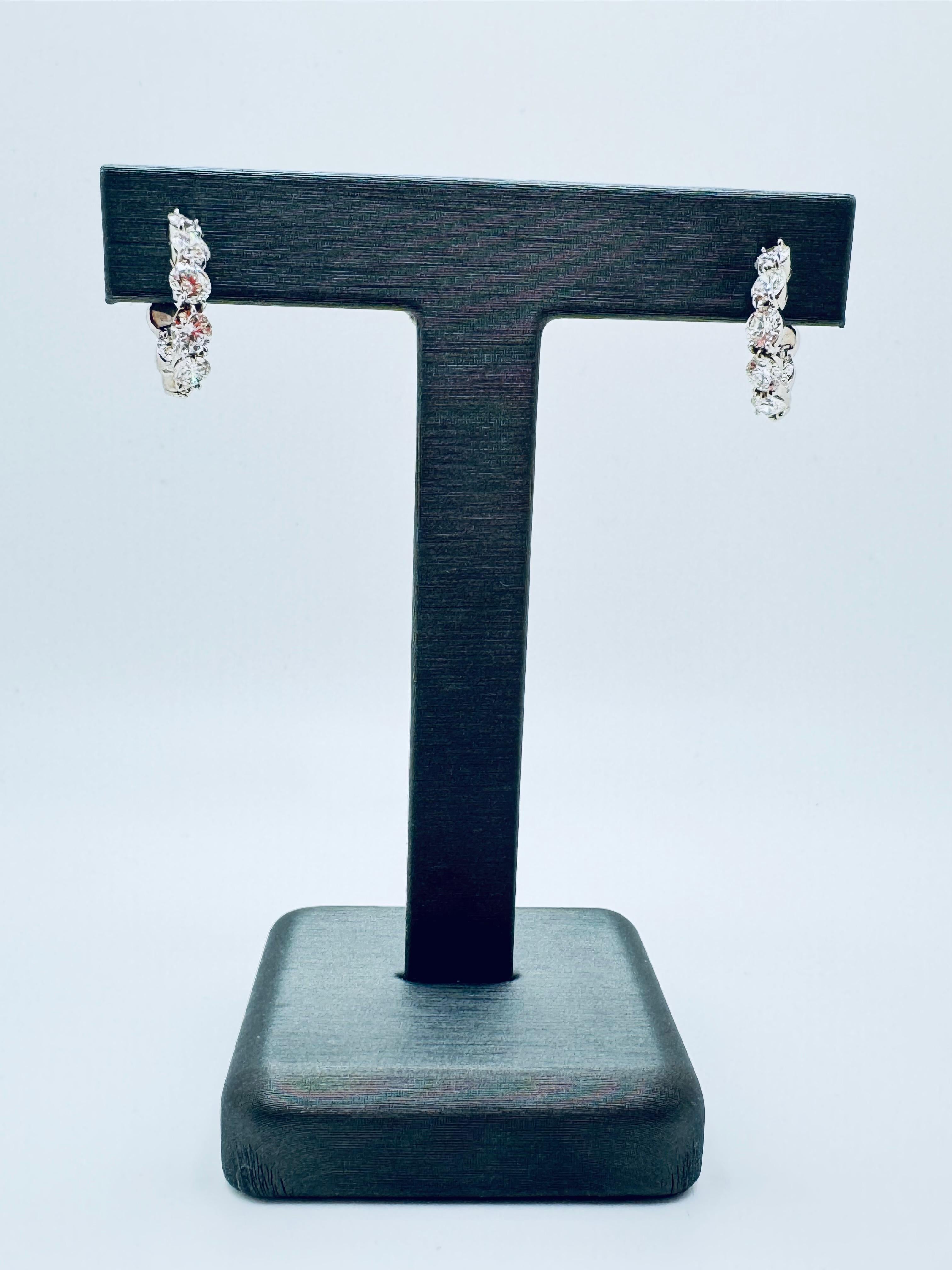 Ces luxueuses boucles d'oreilles torsadées en or blanc 18 carats présentent un équilibre étonnant d'élégance et de brillance. Chaque anneau est serti de sept diamants ronds de taille brillant, stratégiquement placés avec cinq à l'avant et deux à