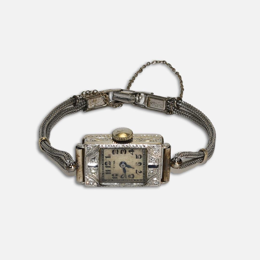 Ladies' vintage Cyma wristwatch in 18k white gold with diamonds and blue sapphires. 
The inside of the case is stamped 18k. 
The manual wind movement is a precision Swiss 17 jewel mechanism. 
Wind twice a day, about 8 turns, but never wind tight.
If
