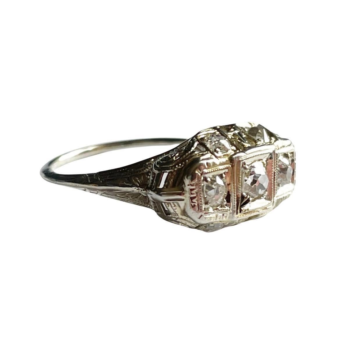 This Art Deco beauty is crafted in 18K white gold, the cathedral shanks are elegantly engraved with swirling geometric designs. Adding to the gallery, on either side are two old mine cut diamonds. Giving a unbelievable luster all the way around the
