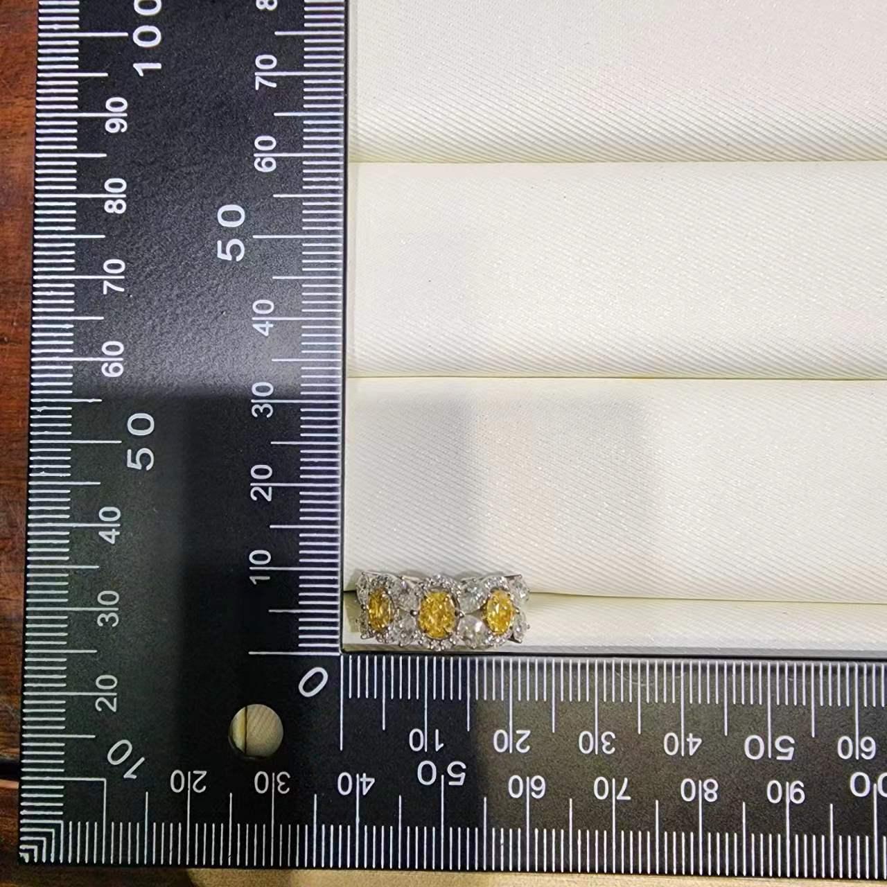 This exquisite 18-karat white gold ring beautifully marries traditional elegance with a touch of contemporary flair, making it a standout piece in any jewelry collection. At its center, the ring features three remarkable fancy yellow diamonds,