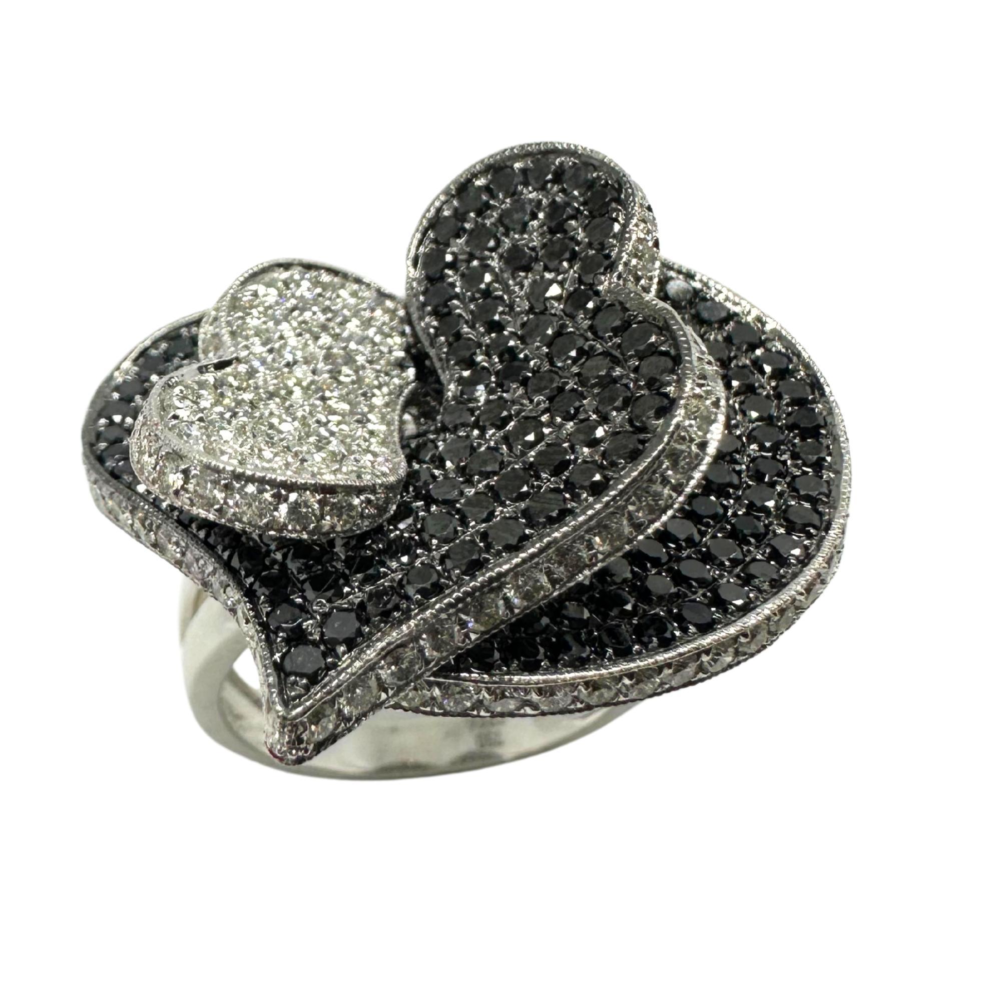 Questo anello in oro bianco 18 carati, audace e artistico, presenta un sorprendente design a doppio cuore ornato da una serie di scintillanti diamanti bianchi e neri. L'incastonatura a pavé a contrasto mette in risalto la brillantezza di 1,17 carati