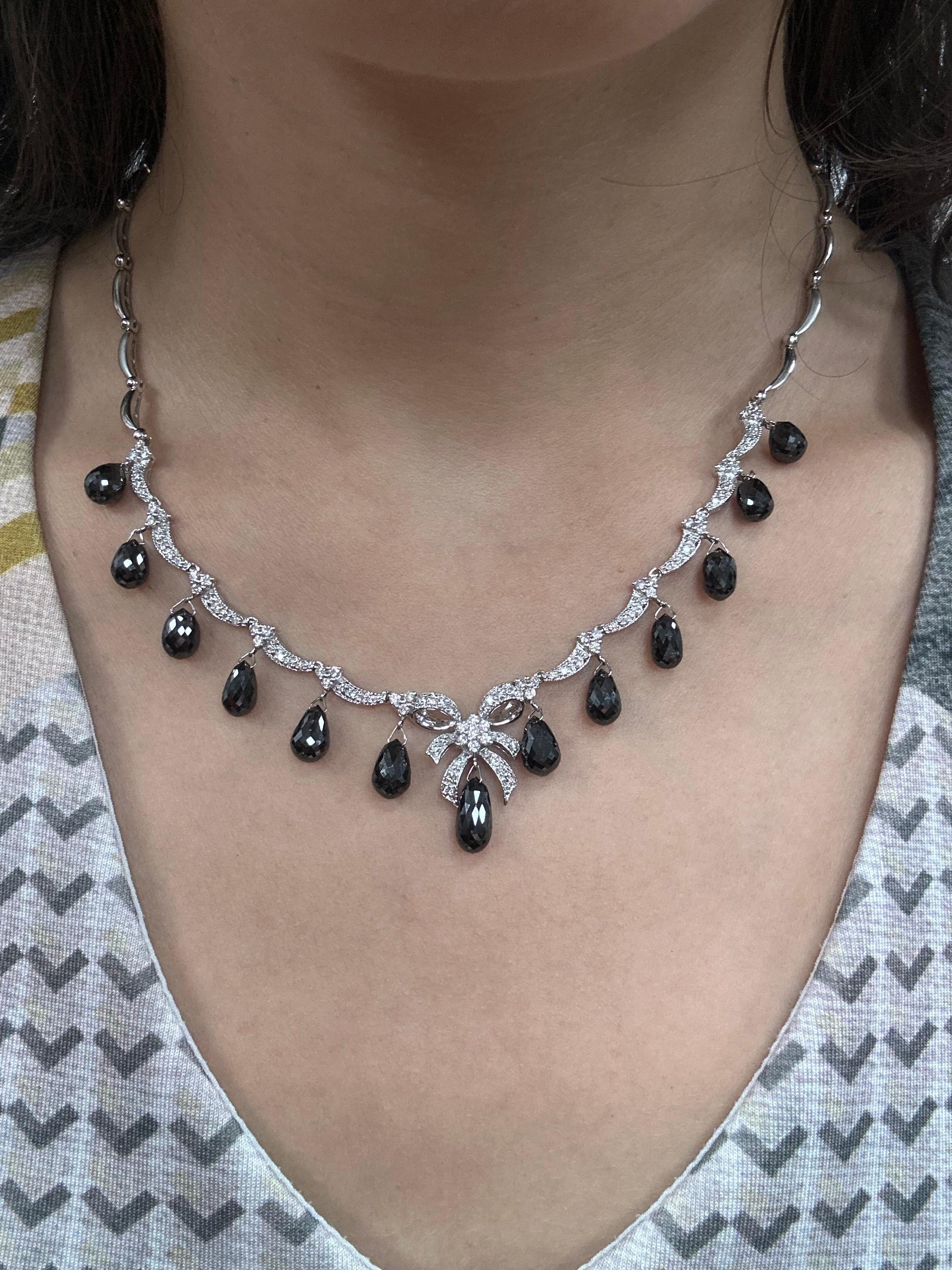 Ein auffälliges Schmuckstück mit 27,51 Karat schwarzen Diamanten im Briolett-Schliff, akzentuiert von 1,20 Karat funkelnden weißen Diamanten in einem anmutigen Bogenmotiv. Diese 16,5 cm lange Halskette aus 18 Karat Weißgold schmiegt sich elegant an