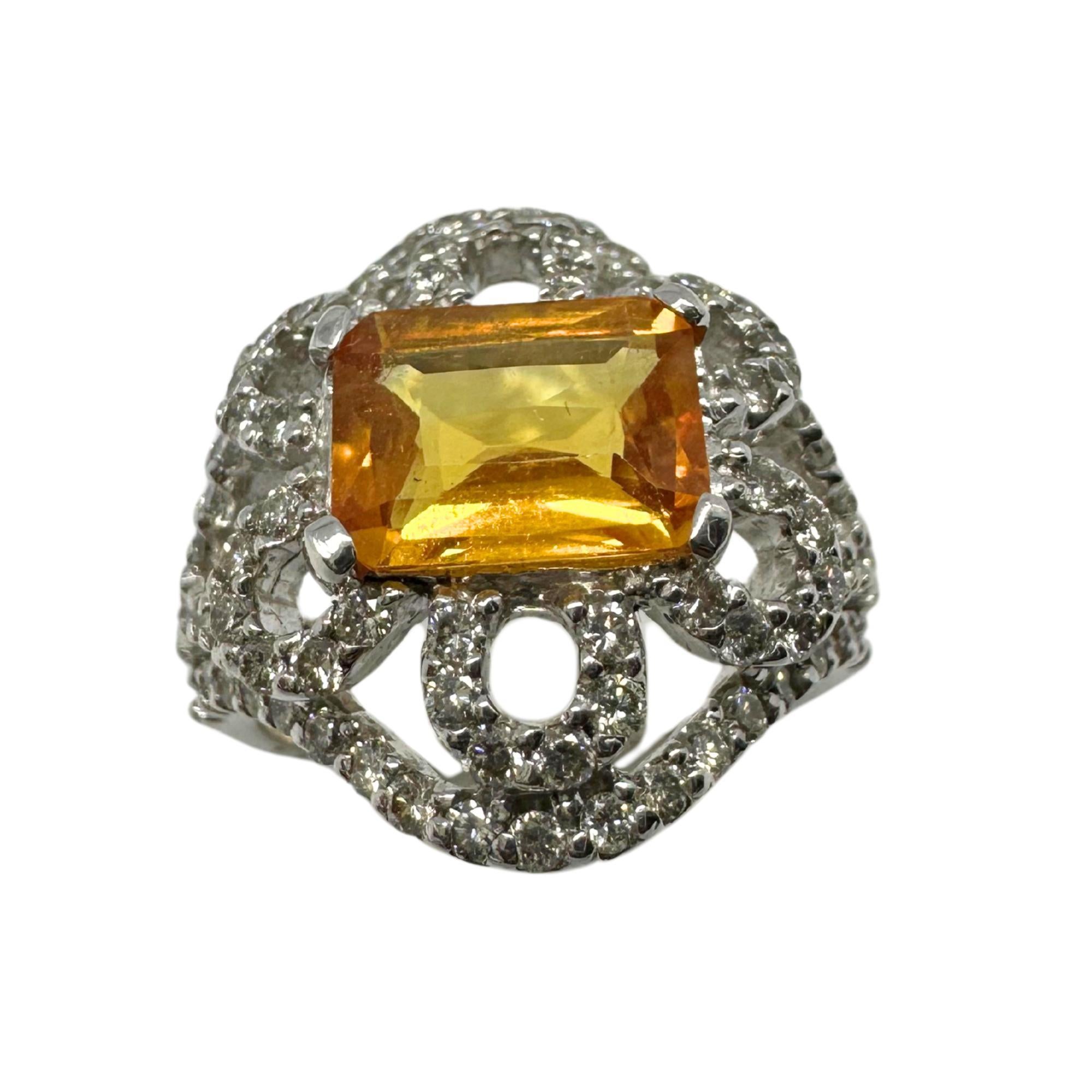 Cette bague en or blanc 18 carats est ornée d'un saphir jaune de 2,33 carats à la teinte dorée éclatante. La pierre centrale est entourée de 1,19 carats de diamants dans un motif floral ajouré. Pesant 8,18 grammes et marquée 