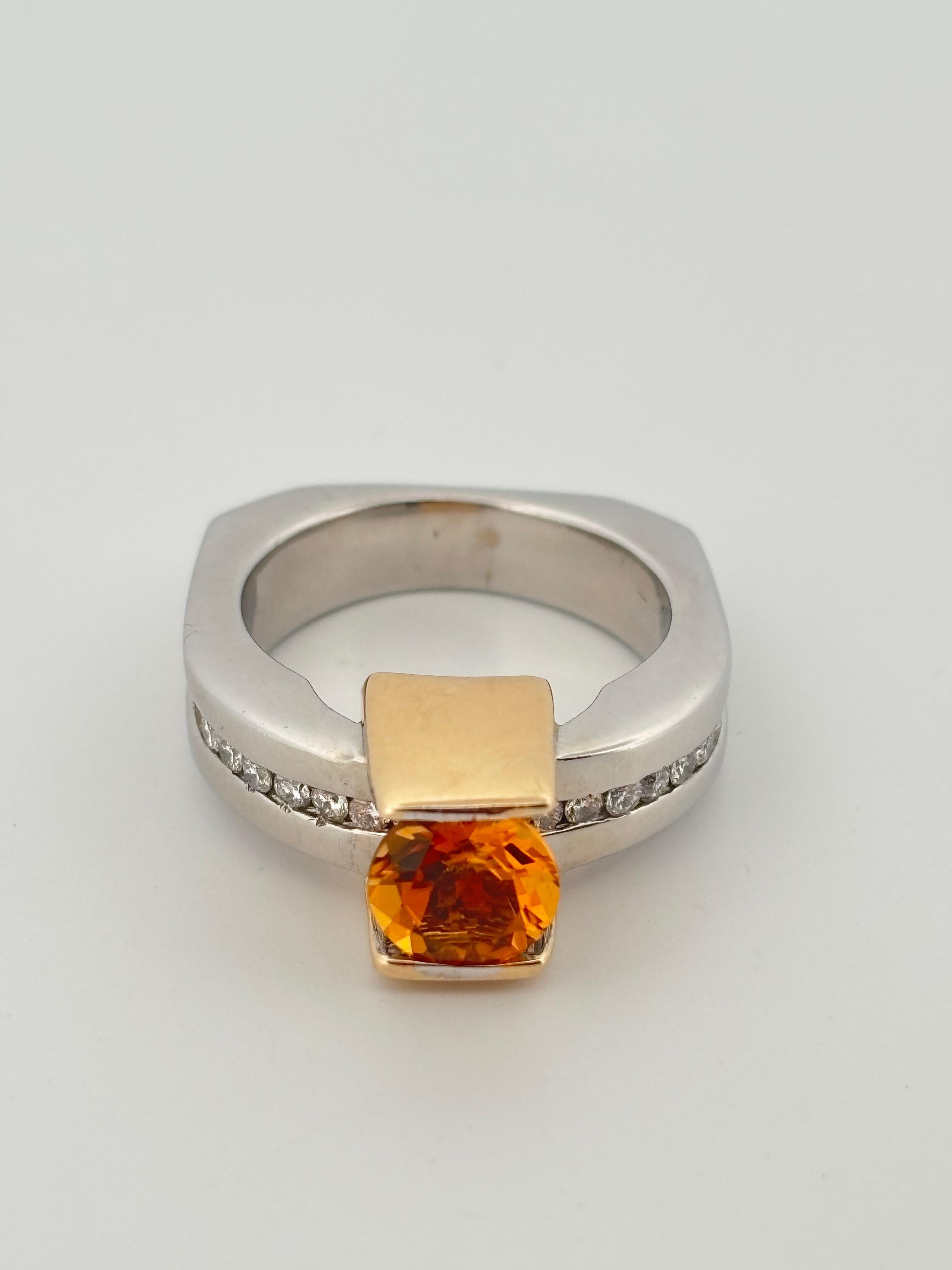 This striking contemporary ring is crafted in 18k white and yellow gold, showcasing an architectural, modernist design. At its center rests a vivid 1.10 carat round-cut citrine, bezel-set in a sleek yellow gold frame that adds warmth and contrast to