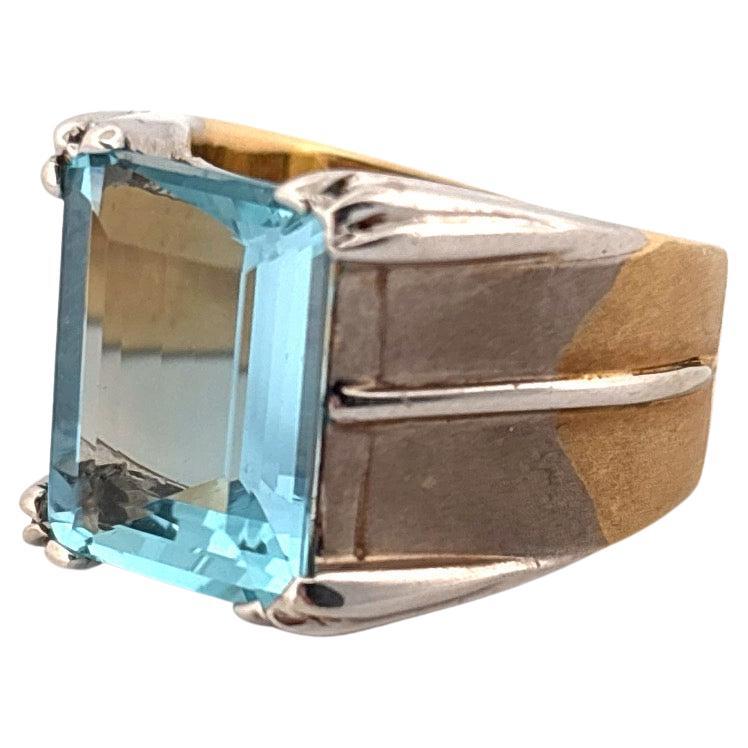Questo straordinario anello in oro bianco e giallo 18 carati mette in mostra un'affascinante acquamarina blu con taglio a smeraldo da 5,10 carati, che emana eleganza e stile senza tempo. L'incantevole tonalità blu freddo dell'acquamarina è