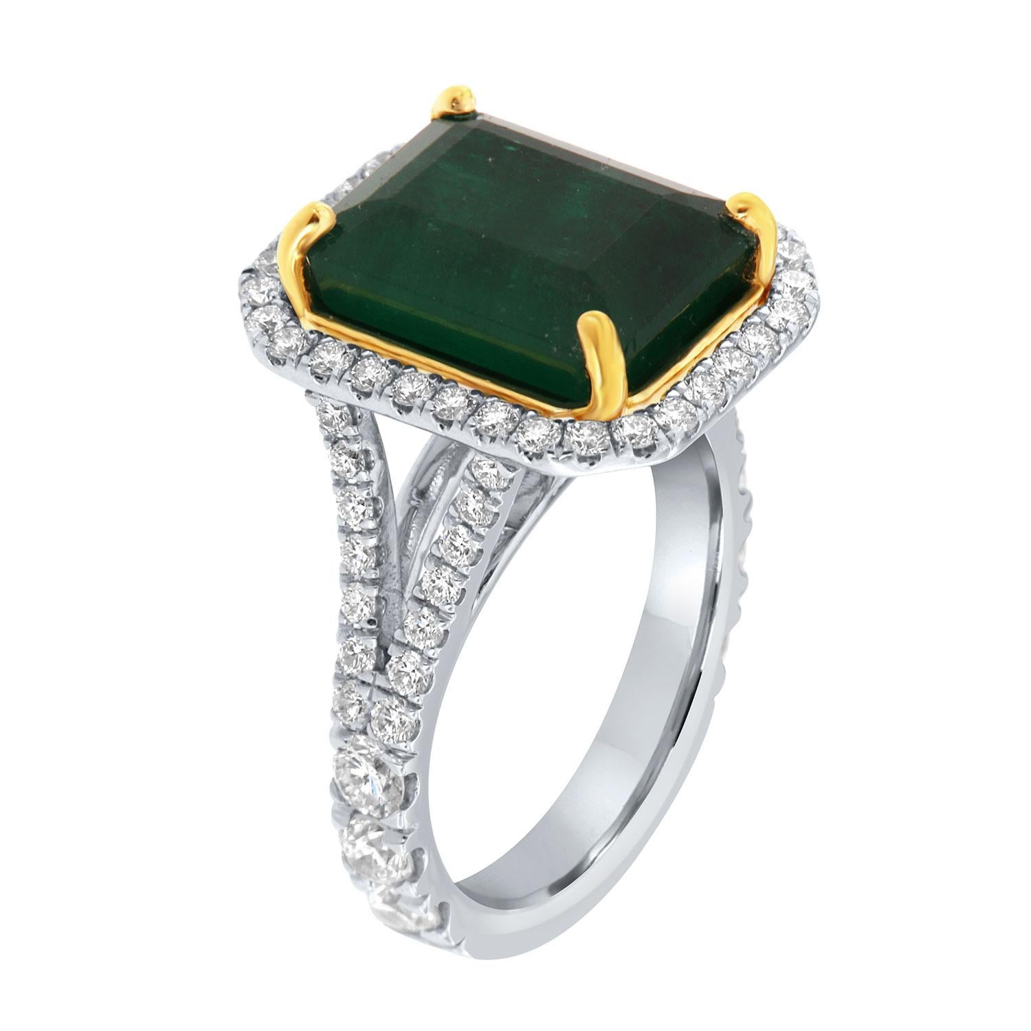 Cette bague en or blanc et jaune 18 carats est ornée d'une émeraude verte naturelle de 6,82 carats provenant de Zambie. Il est entouré d'un halo de diamants ronds brillants sur un anneau à tige fendue de 3,5 mm de large. Les diamants sont sertis sur