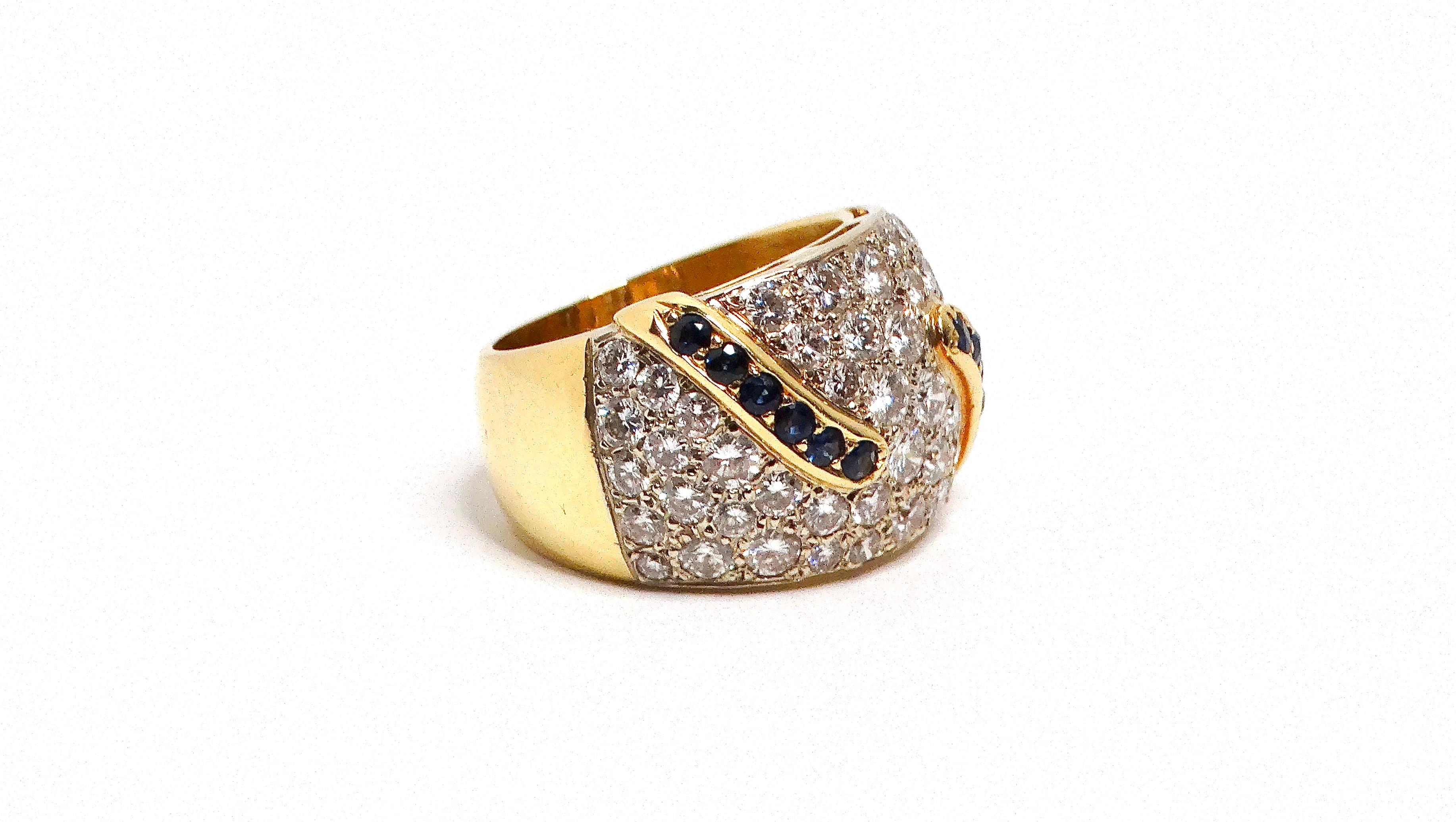 The 18k Yellow and White Gold Diamond and Sapphire Cocktail Ring is a breathtaking fusion of elegance and luxury. This cocktail ring features a dazzling array of diamonds, all pave set in a white gold plate, creating a sparkling focal point. The