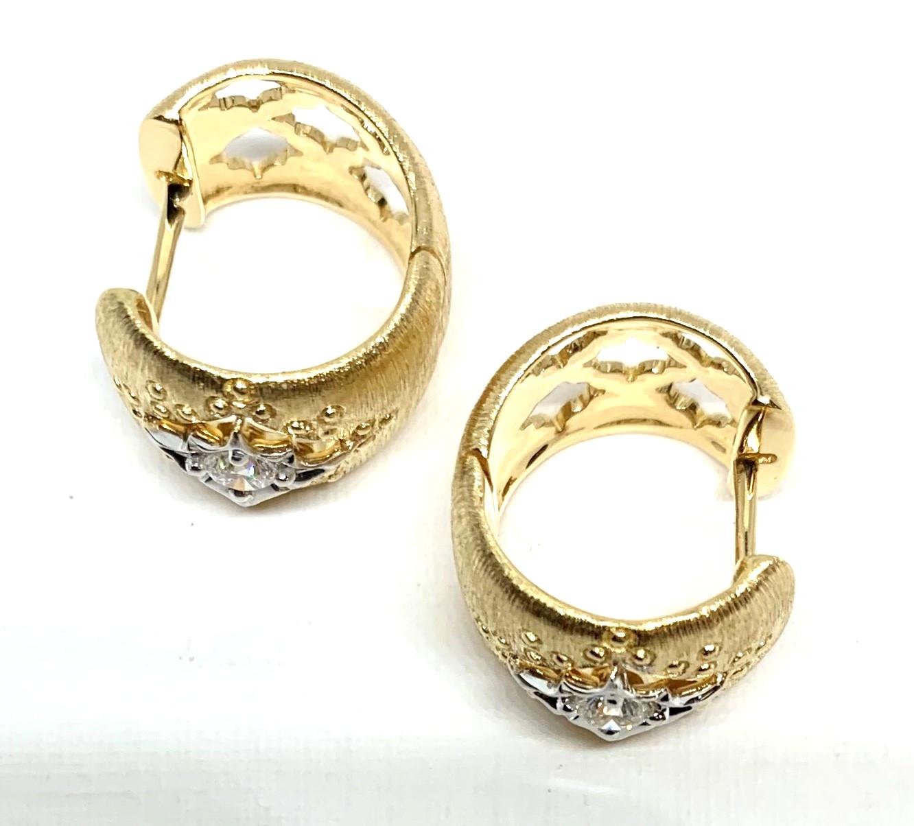 These Florentine inspired hoops feature two round, brilliant cut diamonds set in 18k yellow and white gold earrings with hinged backs. With lovely open gold work and refined, textured details, these earrings are beautiful from the front and the back
