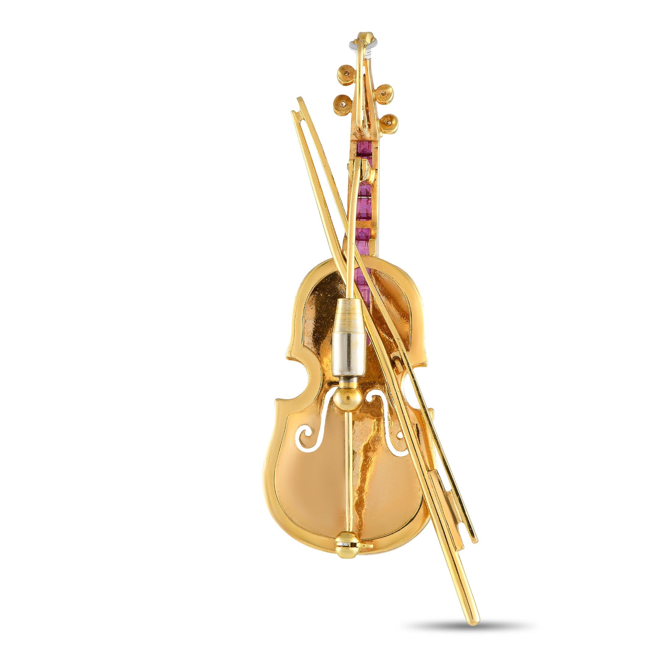Inset Ruby gemstones totaling 1.0 carats and sparkling Diamonds with a total weight of 0.15 carats add extra dimension and depth to this exquisite brooch. Shaped like a violin, this intricate accessory is crafted from 18K Yellow Gold and measures