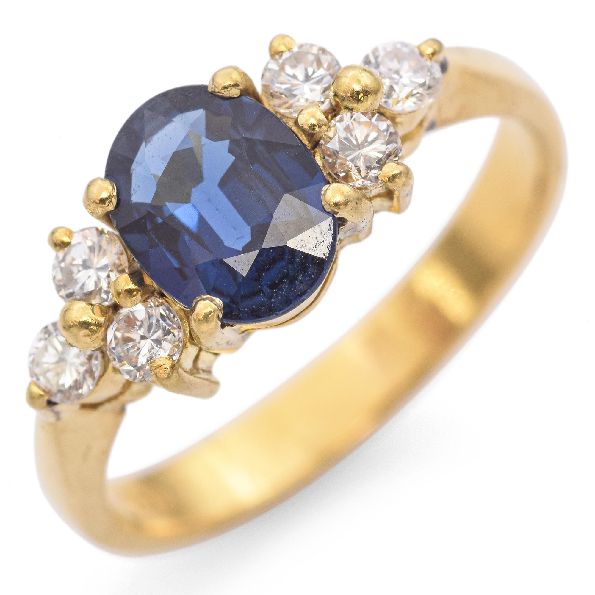 This captivating ring showcases a stunning 0.81 carat oval blue sapphire, its deep hue drawing the eye to the center. Flanking the sapphire are clusters of round white diamonds, totaling 0.21 carats, adding a touch of sparkle and contrast. The