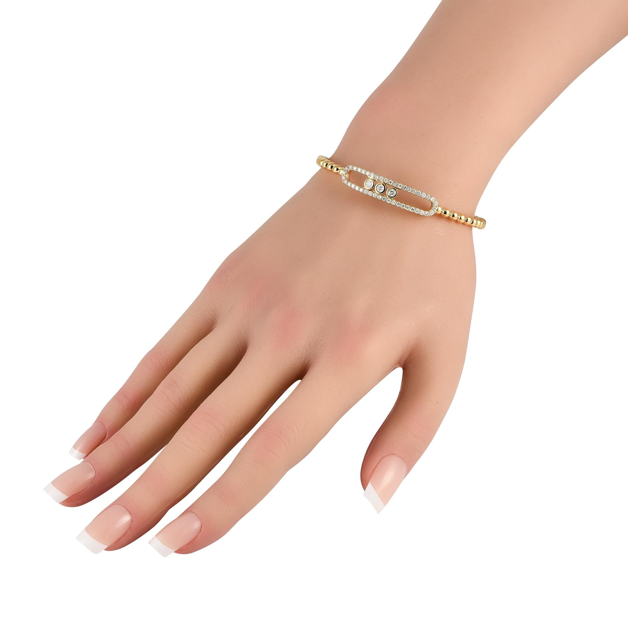 This 18K Yellow Gold bangle bracelet will never go out of style. Elegant and understated, this impressive accessory combines a beaded band with sparkling Diamonds totaling 0.85 carats - including a trio of bezel set Diamonds at the center of the