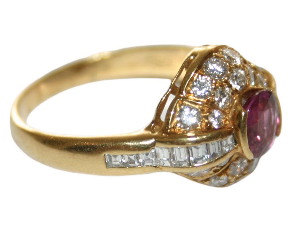 This women's beautiful, cluster style 18 karat yellow gold ring weighs 5.50 grams.
It contains a center 5.5x5mm oval shaped natural ruby mounted in a bezel setting, with a carat weight of approximately 0.50.
This ruby is surrounded by baguette,