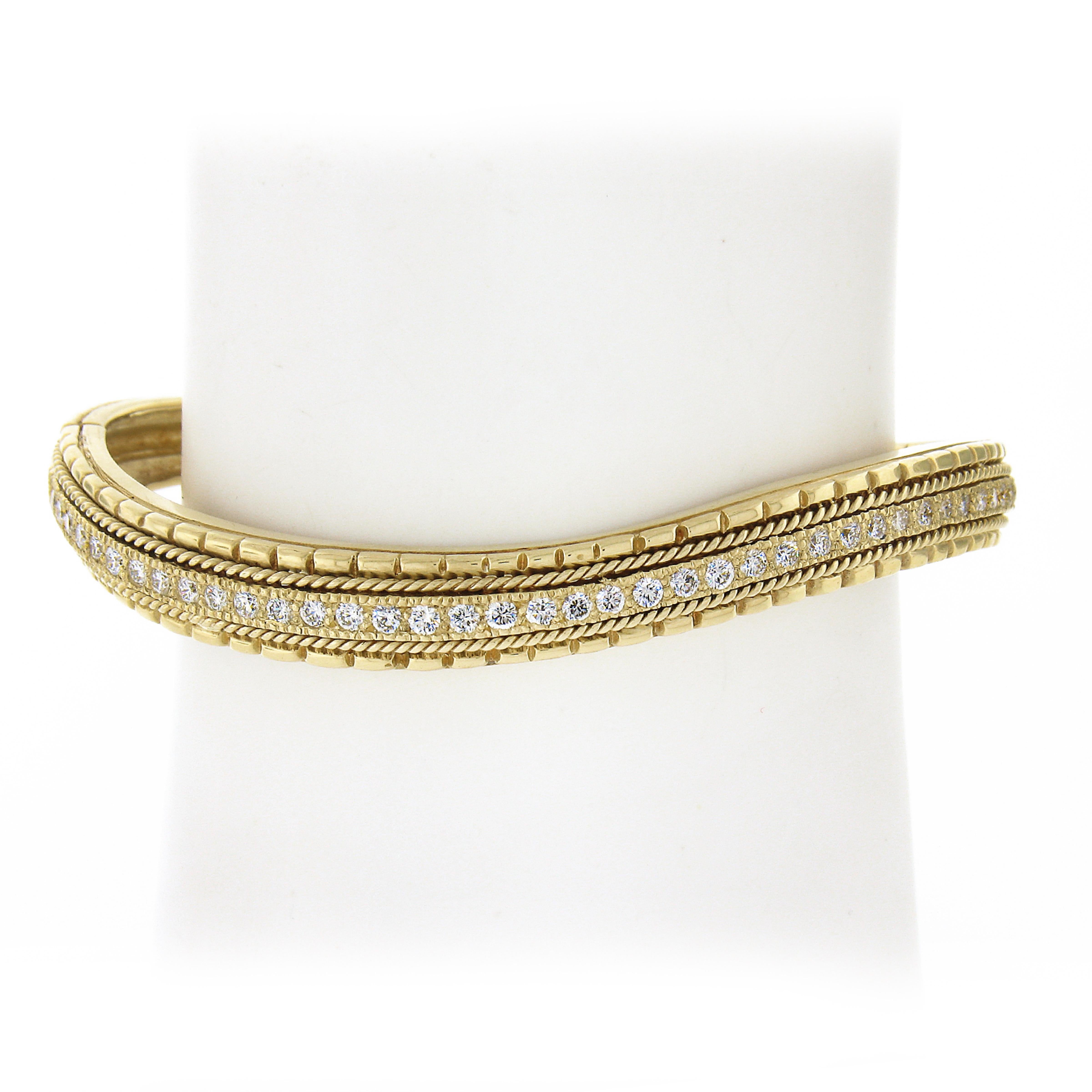 This amazing wavy bangle bracelet is crafted in solid 18k yellow gold, featuring 40 round brilliant cut top quality diamonds throughout its center. Each of the fiery diamonds is perfectly pave set totaling 1.14 carats in weight. The sides are framed