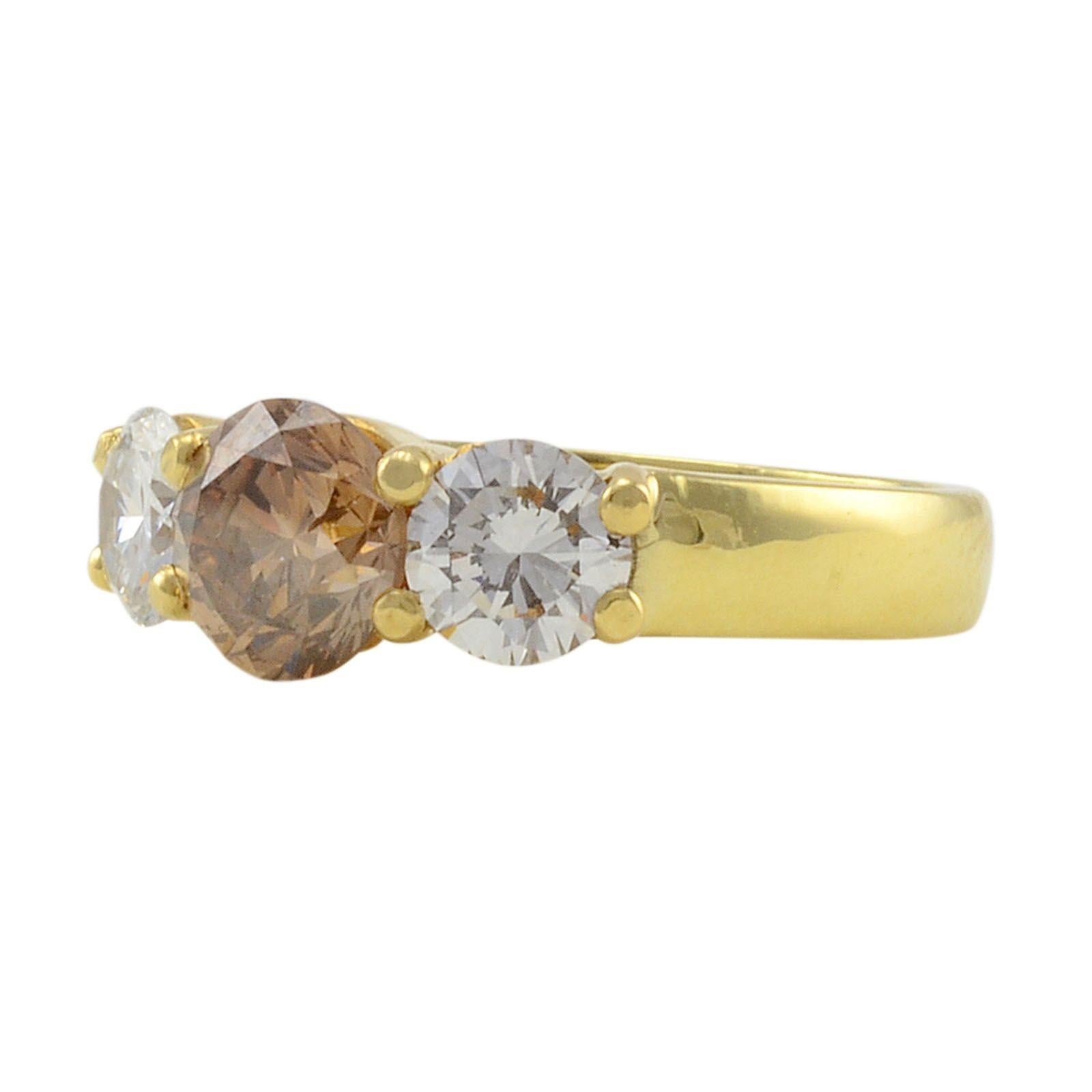 Estate 18K yellow gold 1.35 carat light brown diamond ring. This ring has a center round brilliant diamond at 1.35 carats and two side round brilliant diamonds, one at 0.61 carats and one at 0.59 carats, SI1 clarity H-I color. This estate diamond