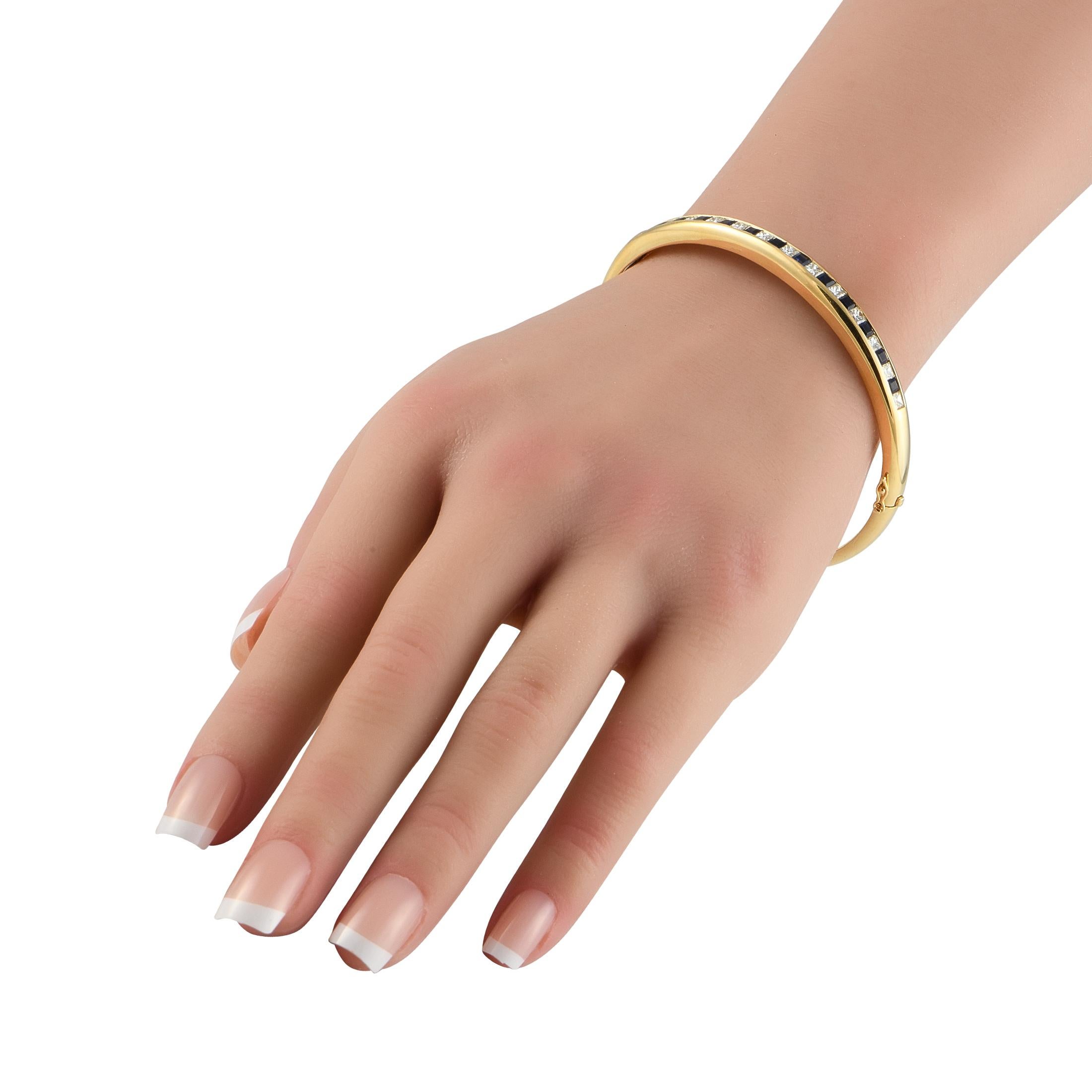 Ajoutez une touche de luxe à n'importe quel ensemble avec ce bracelet bangle élégant et sophistiqué. Au centre du motif, des diamants de taille carrée totalisant 1,50 carat alternent avec des saphirs totalisant 1,80 carat. La monture élégante en or
