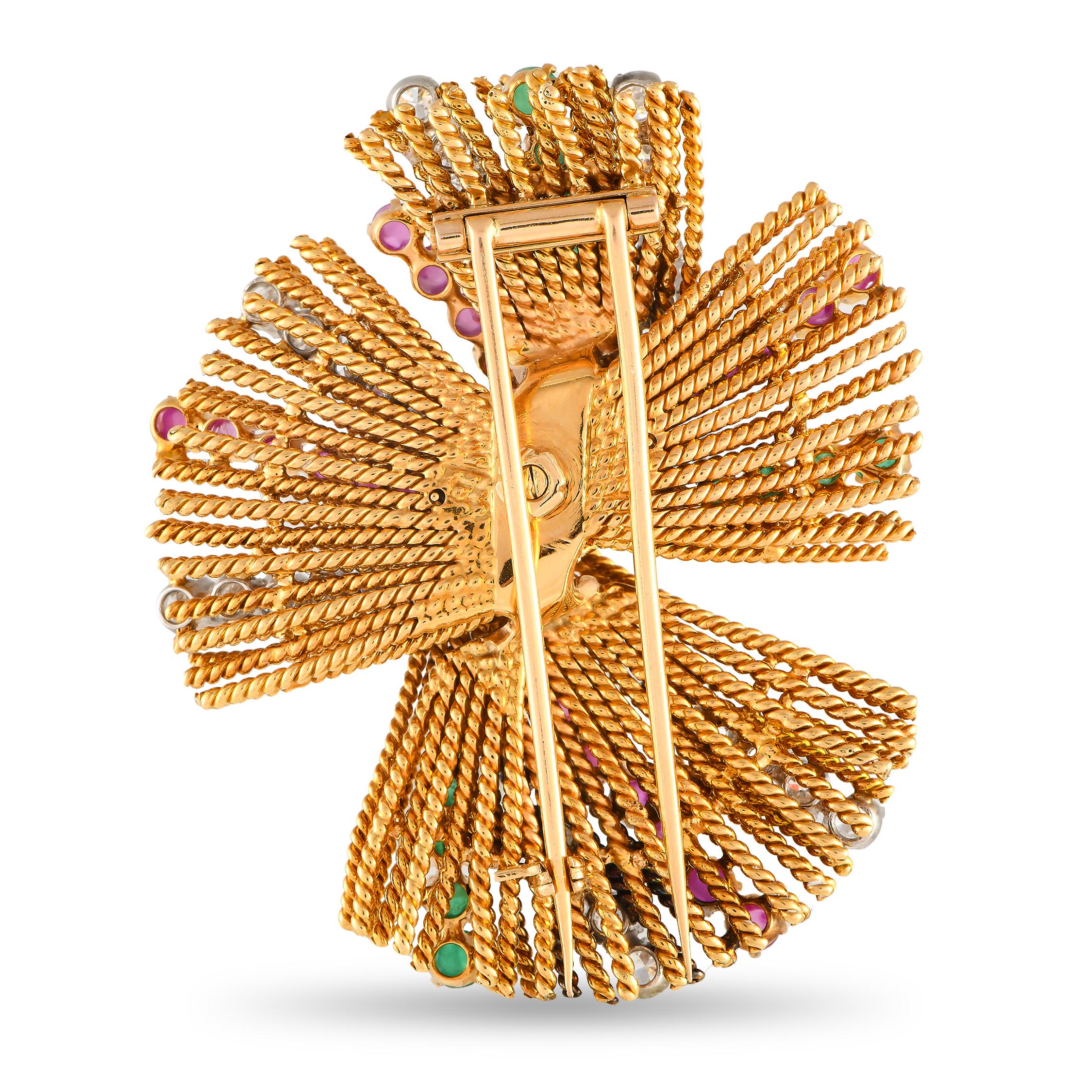 This dynamic 18K yellow gold brooch is a celebration of color, texture, and design. A series of diamonds totaling 2.50 carats are elevated by ruby gemstones totaling 3.10 carats and emeralds with a total weight of 1.50 carats. Rope-like accents add