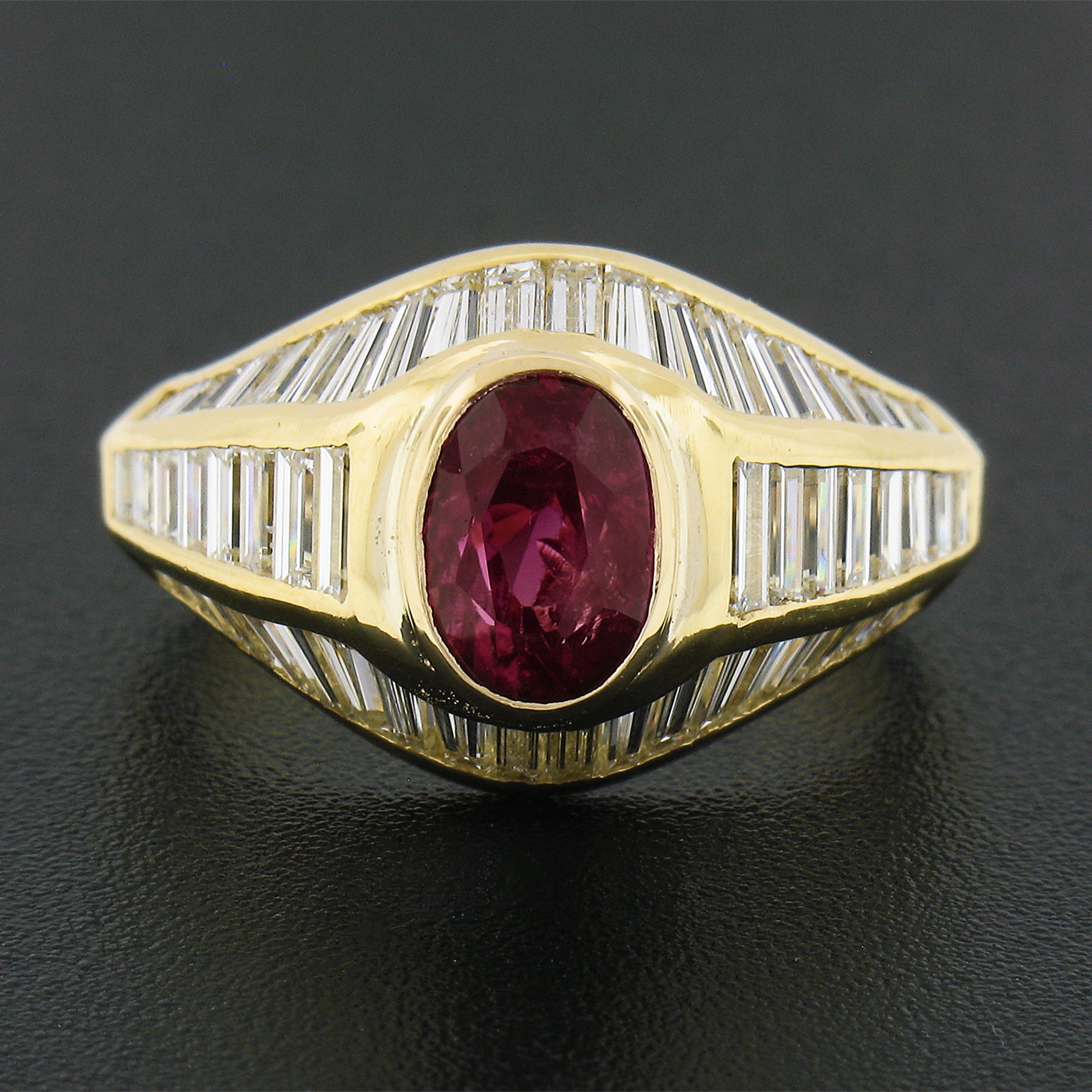 This elegantly and well refined ruby and diamond cocktail ring is crafted in solid 18k yellow gold and features a gorgeous, GIA certified, ruby solitaire neatly bezel set at the raised center. This center stone stands out with its incredible, vivid