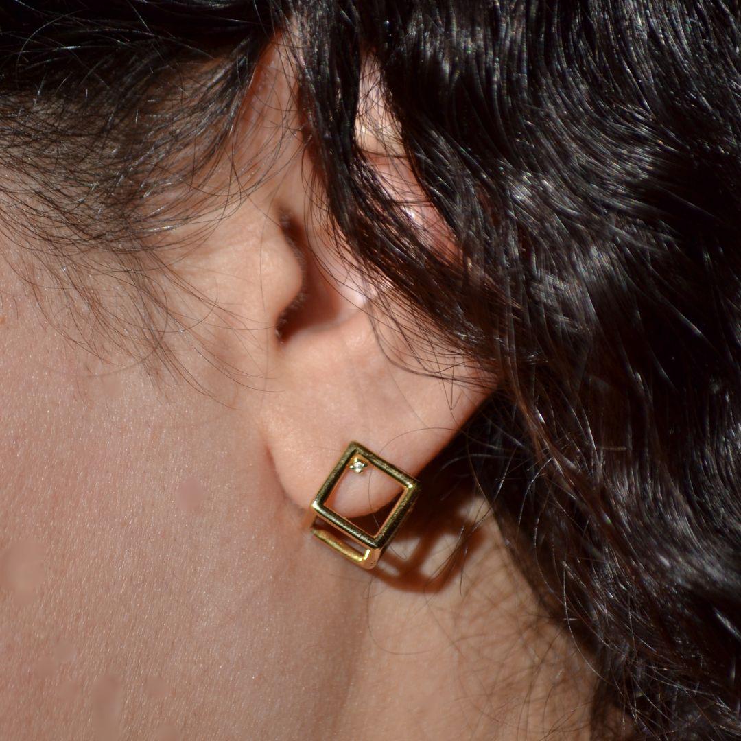 Adoptez l'élégance moderne avec ces boucles d'oreilles 3D cube en or jaune 18 carats, qui présentent un design innovant de cube ouvert qui capte la lumière sous tous les angles. Chaque boucle d'oreille est délicatement rehaussée d'un diamant unique,