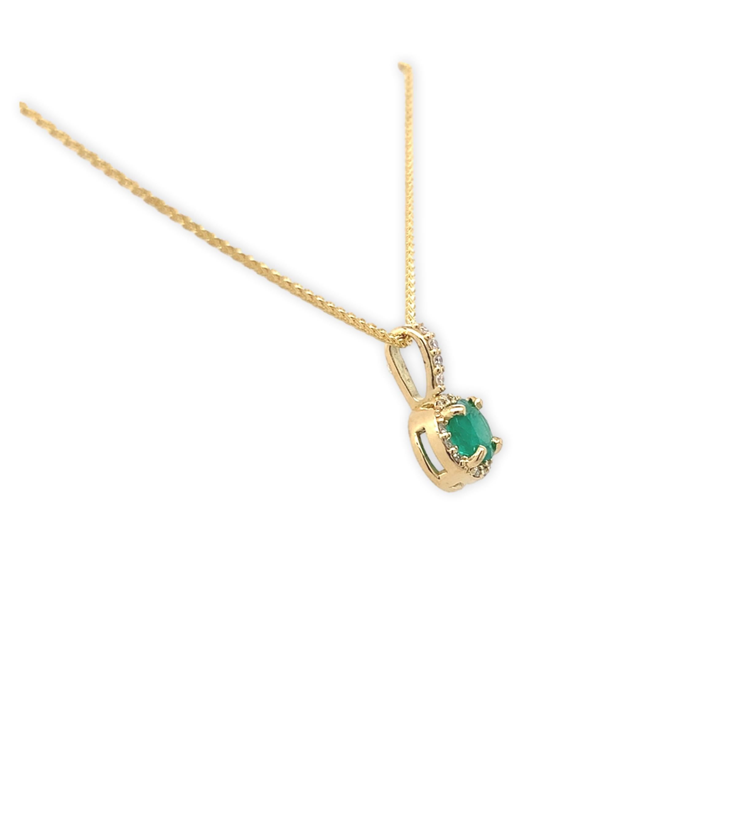 Pendentif en or jaune 18 carats avec émeraude véritable extraite de la terre et halo de diamants. L'émeraude de taille ronde mesure environ 4,5 mm et présente une couleur moyennement foncée et une clarté fine. L'émeraude pèse 0,40 carat. Il y a 16