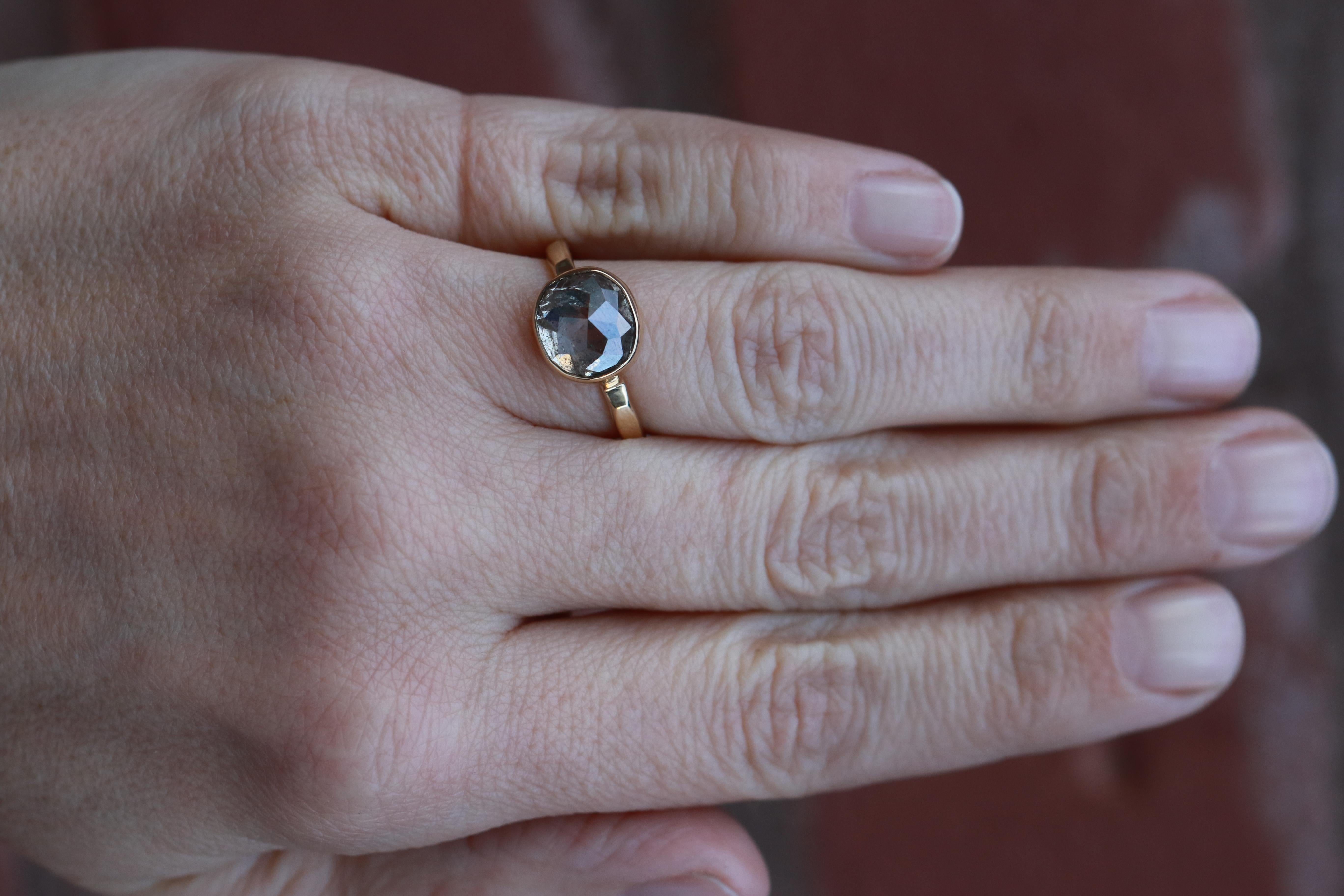 A bezel envelops a seriously sizable rustic diamond with a smoky grey salt and pepper color profile, set on a hammered gold band.

Recycled 18 Karat Gold
Oval Rosecut Diamond, 4.82ct, salt + pepper, 9.8x8.9x5.9mm
One of a Kind Piece