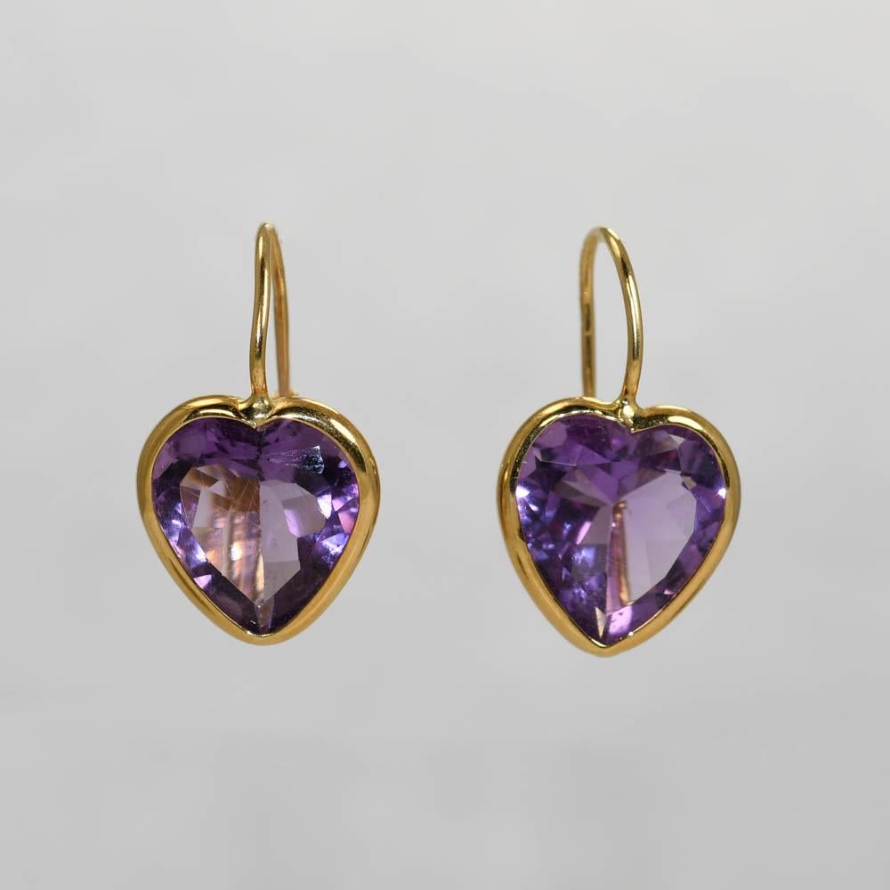 Amethyst heart earrings in 18k yellow gold settings.
Stamped 750 and weigh 3.9 grams gross weight. 
The amethyst hearts measure 12.5mm by 11mm.
One stone has small scratches on the surfaces. 
There are wire clips for pierced ears. 