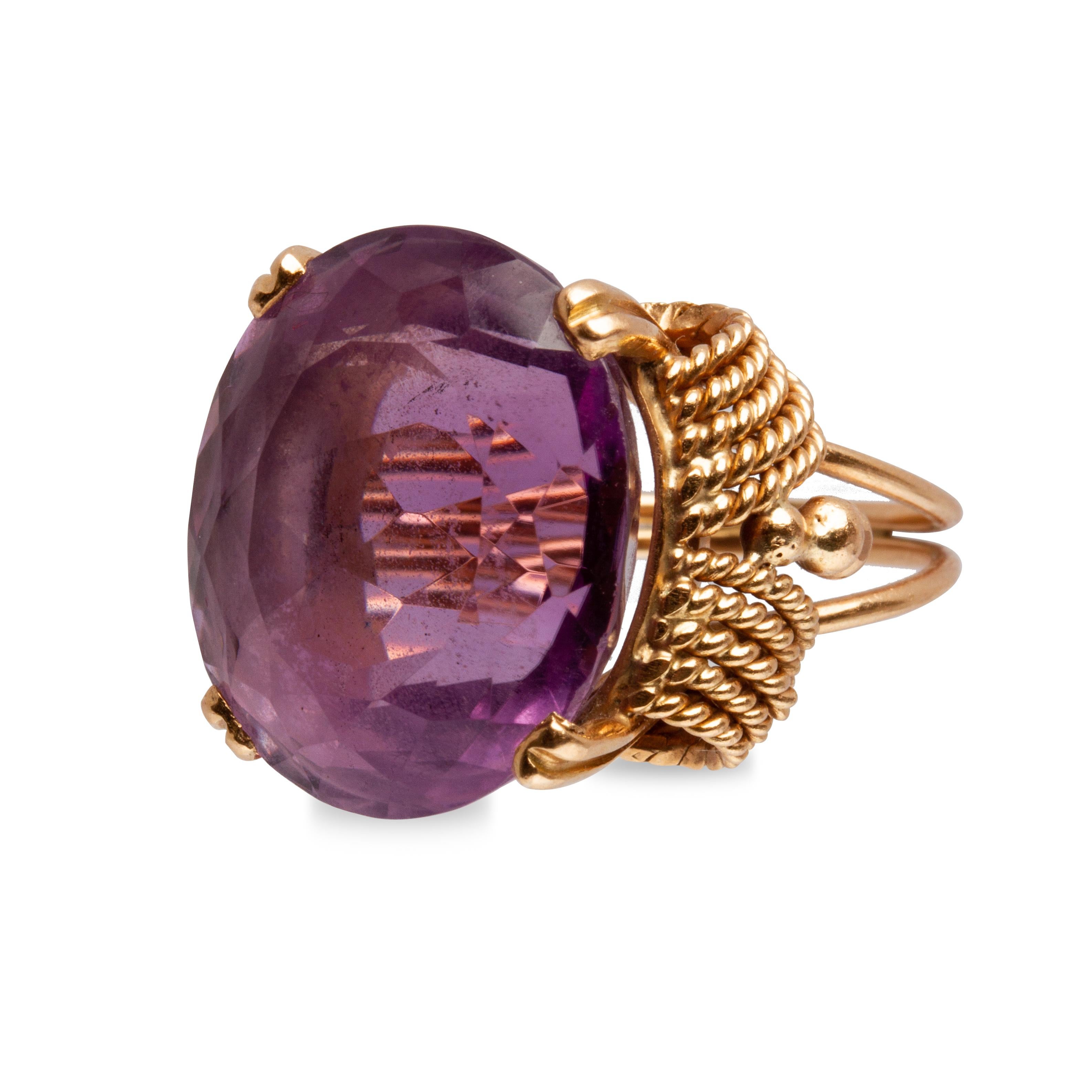 Offered is an 18k yellow gold cocktail ring, high mount 19.44 ct amethyst stone with 4-prong setting, side rope motifs, beading, and a split shank. The ring weighs approximately 7.70 dwt. 5.75 ring size; 18.5 mm x 16.4 mm x 12 mm