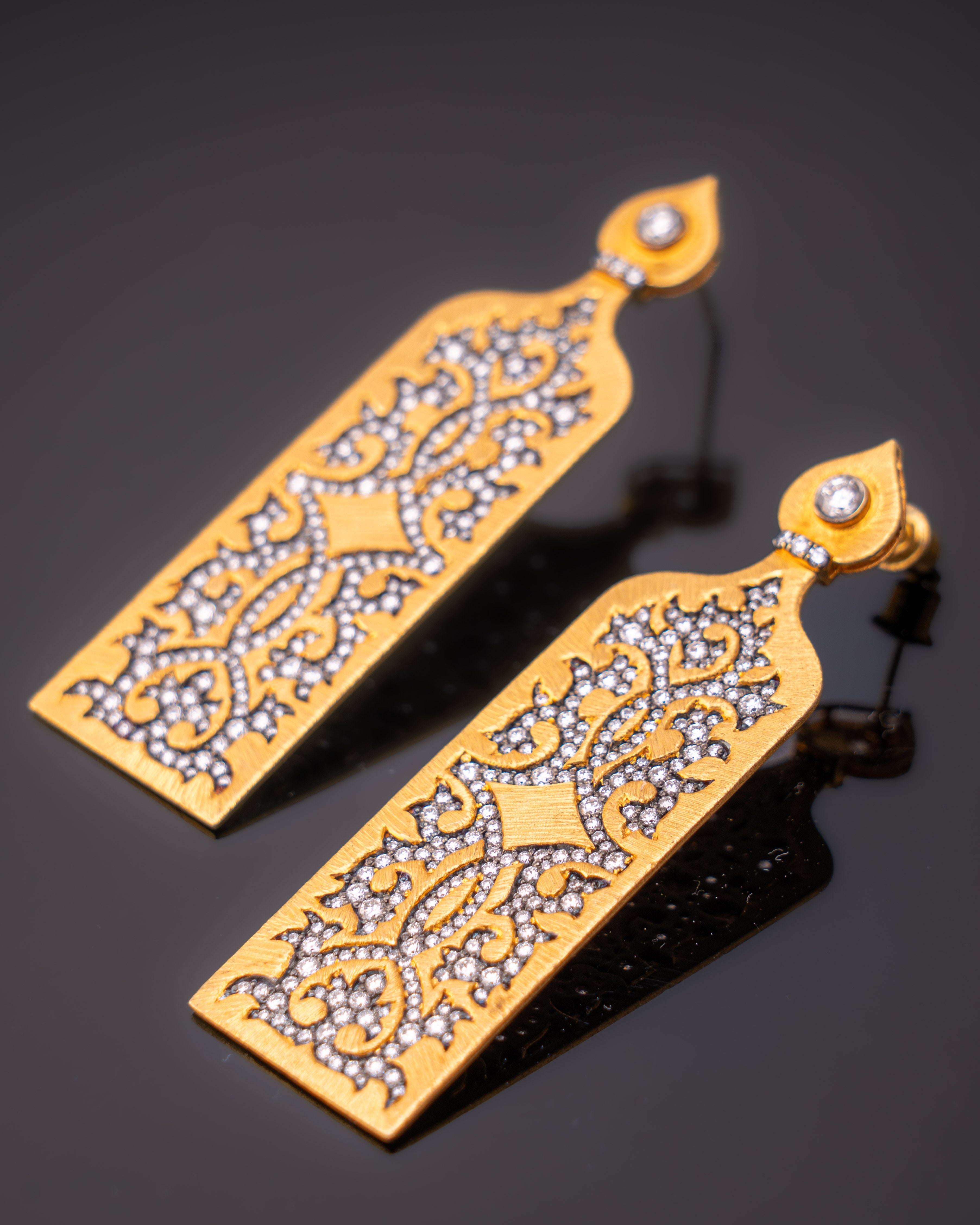 A beautiful pair of 18K Yellow Gold dangle earrings, studded with VS quality White Diamonds with black rhodium polish. The earrings are around 2.5 inches long a unique matte finish, giving them a very art-deco vibe. 
We provide free shopping, and we