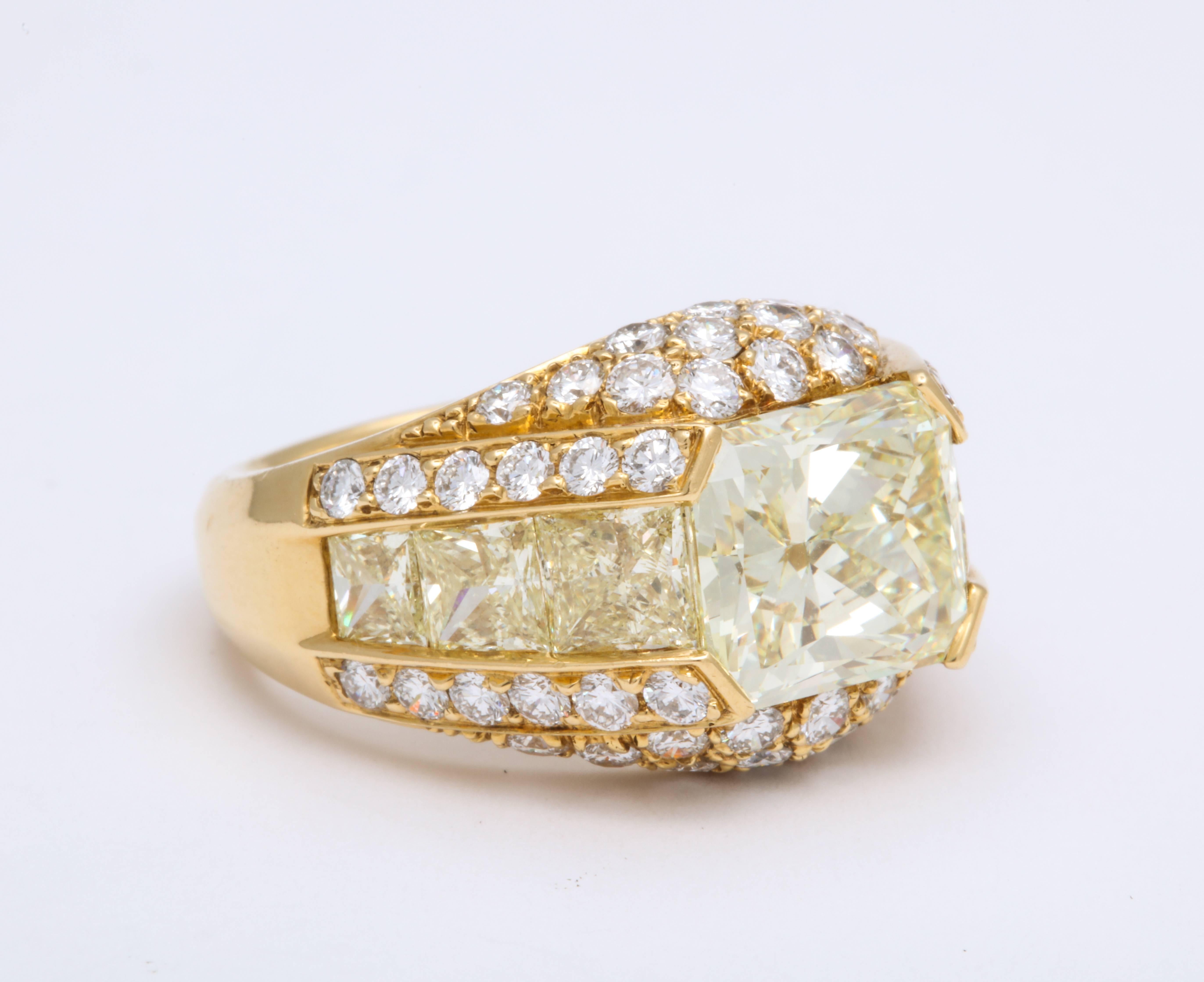 Square shape radiant cut diamond weighing 4.56 carats, natural color X, Y, Z mounted atop contemporary dome ring flanked on an east:west orientation with 6 channel-set, natural fancy yellow princess-cut diamonds weighing 2.39 carats, and finished