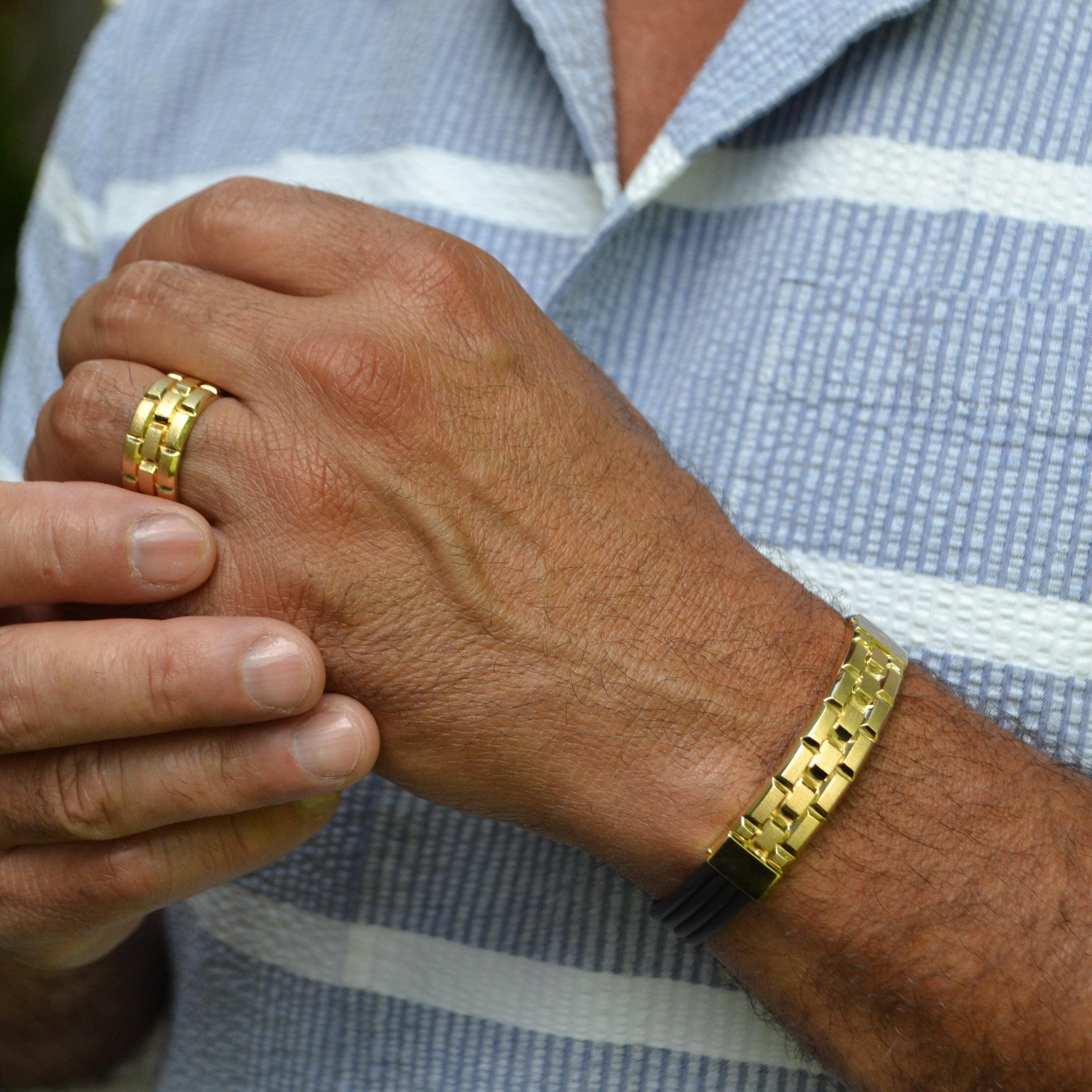 This sophisticated men's bracelet is a modern fusion of elegance and strength, featuring an 18-karat yellow gold centerpiece on a sleek black rubber band. The gold plate showcases a unique interlocking pattern, adding texture and dimension to the