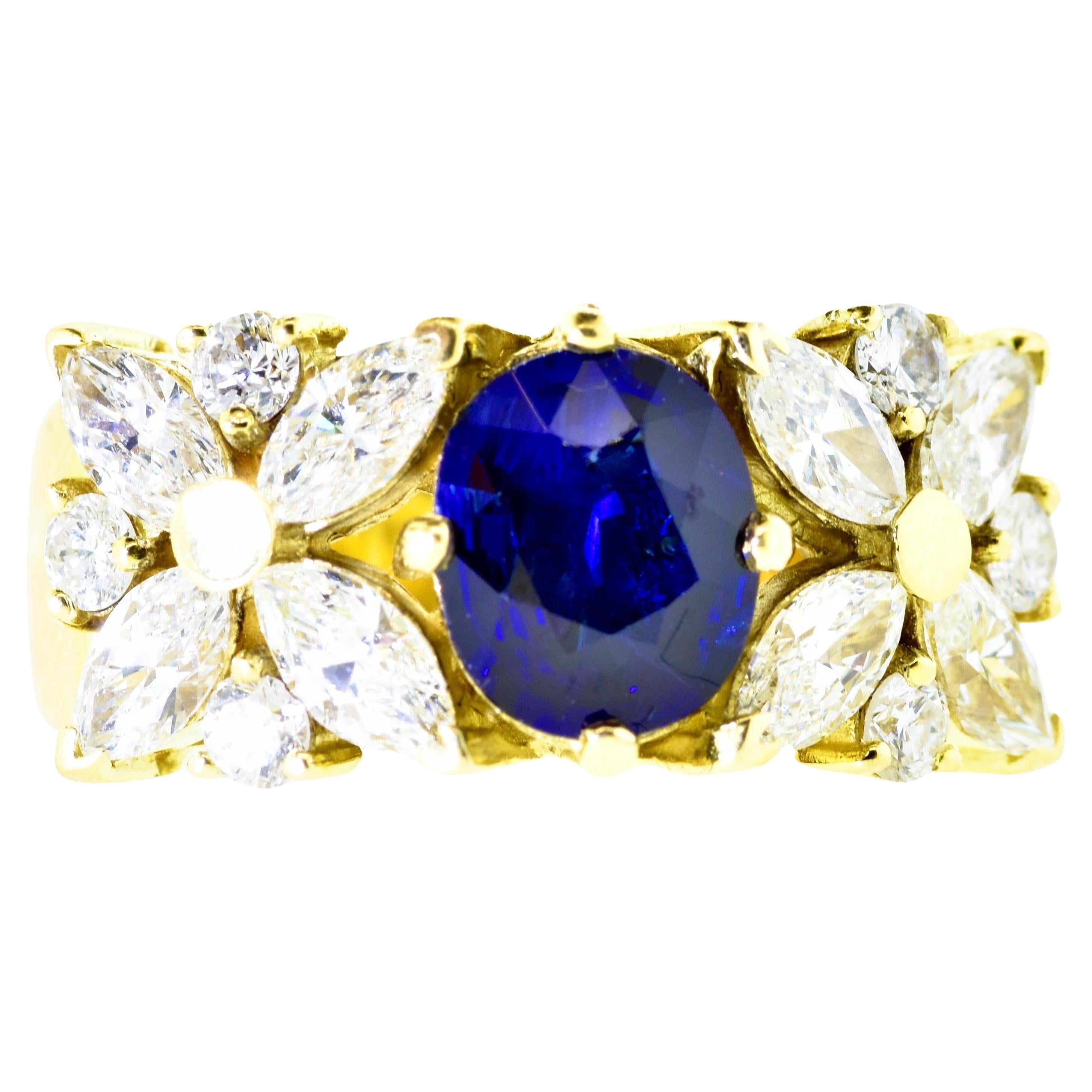Diamond and natural bright Blue Sapphire prong set in a contemporary 18K yellow gold ring. The fine white diamonds are both round brilliant cut and marquis cut. The diamonds average H (near colorless), and VS1 (very slightly included to the first