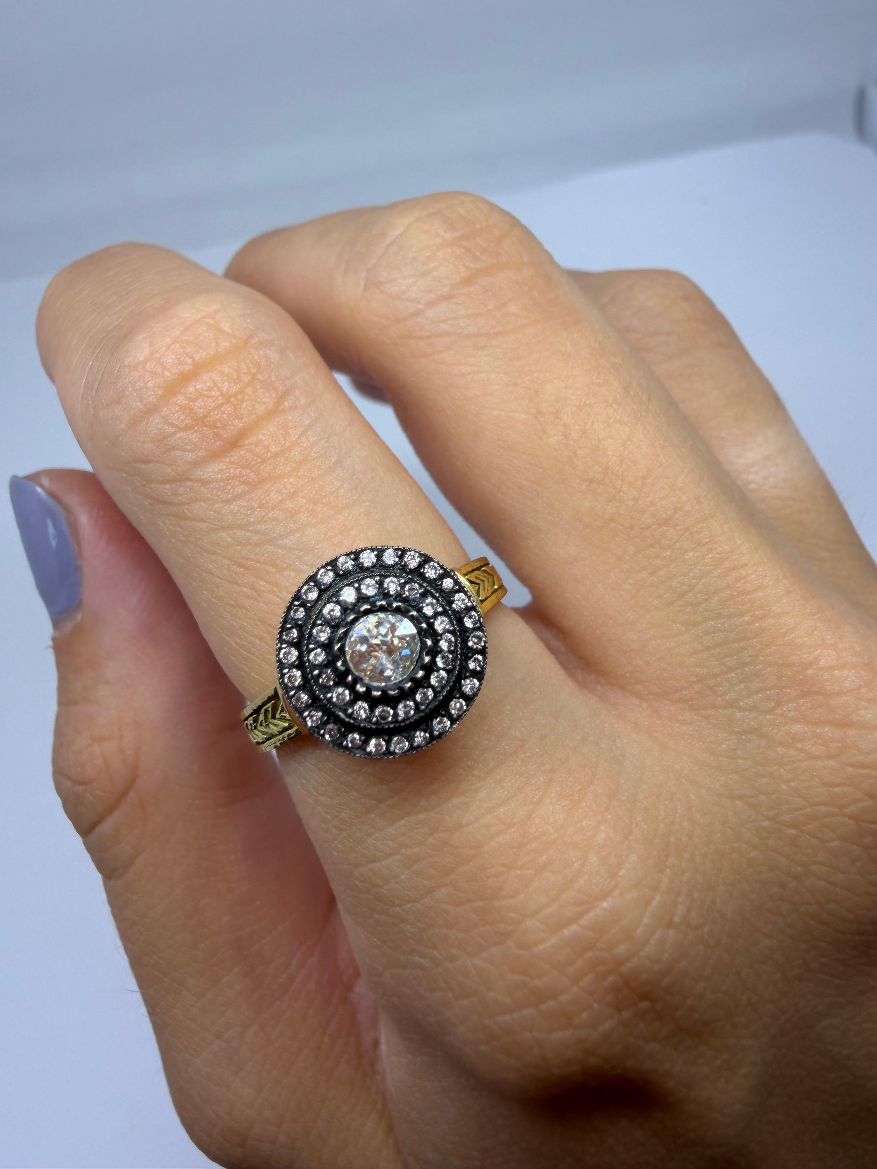 Realizzato in oro giallo 18 carati con la parte frontale in argento, questo anello presenta un diamante taglio rosa da 0,30 carati incorniciato da aloni concentrici di tagli rosa più piccoli. L'incastonatura in argento scuro esalta lo scintillio del