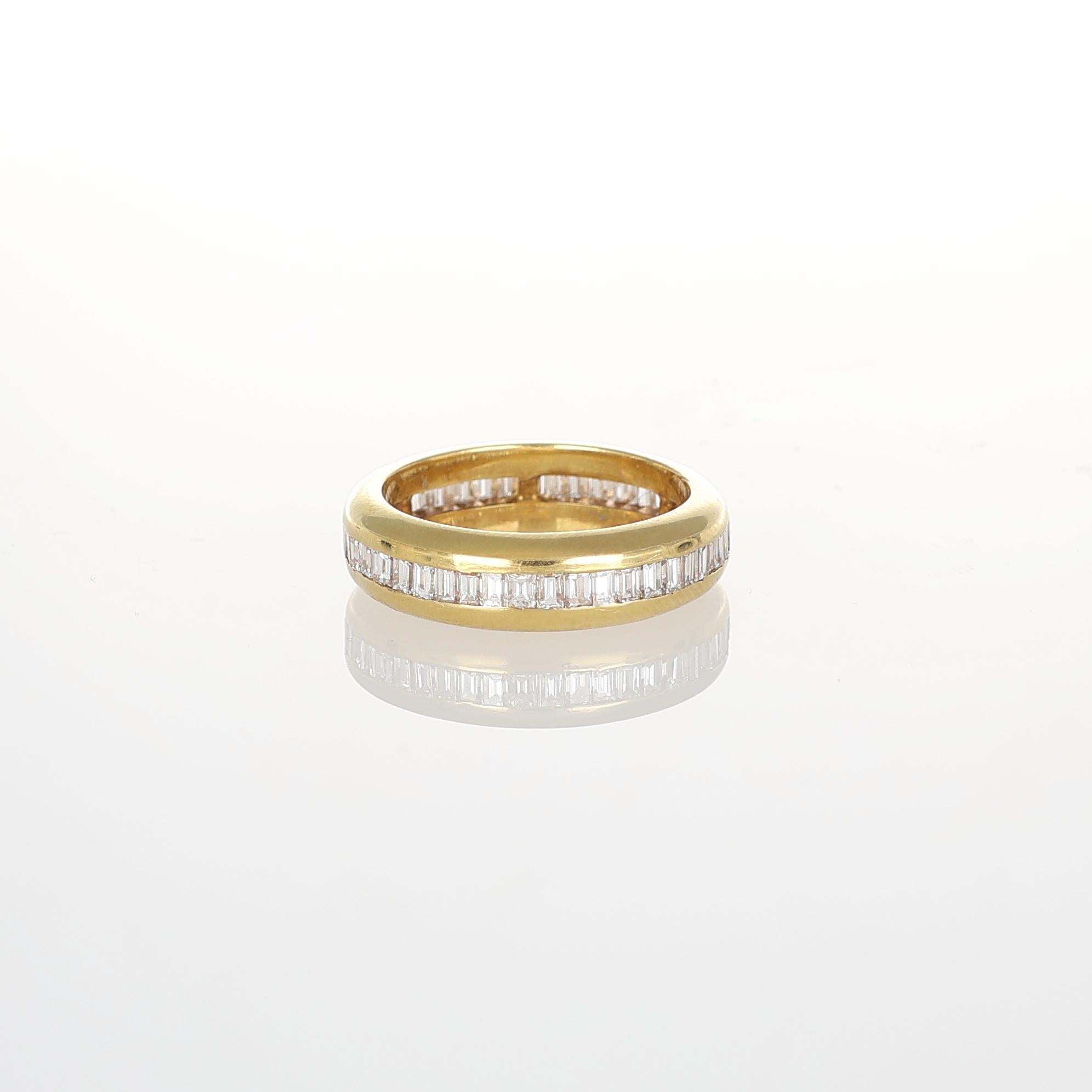 A timeless eternity band crafted in 18K yellow gold, featuring a sleek channel setting of baguette-cut white diamonds totaling 2.40 carats. The precision-cut diamonds create a seamless stream of brilliance, emphasizing the ring’s refined elegance.