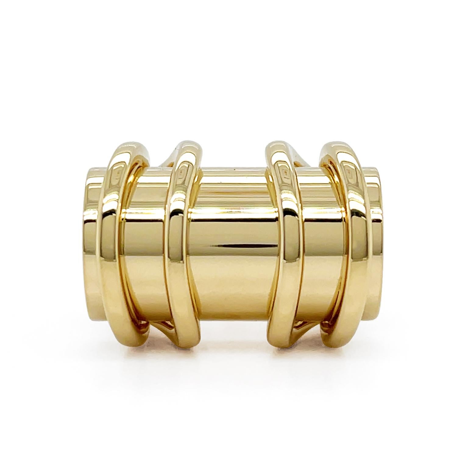 The warm flare of 18k yellow gold is the essence of this intricate and modern ring. A sleek cylinder cabochon is on top of the band. Enveloping over are a pair of parallel golden strands extending on each side from the split shank beneath. Varying