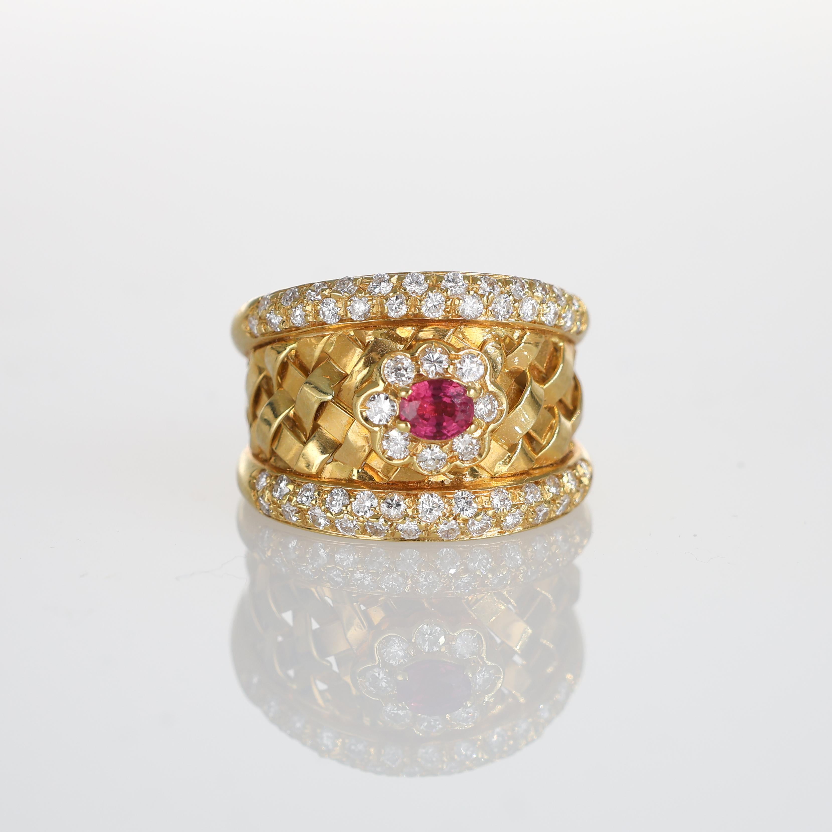 A luxurious wide band ring crafted in 18k yellow gold, showcasing an intricate basket-weave design. At its center, a vibrant oval ruby is framed by a floral arrangement of sparkling brilliant-cut diamonds. Two rows of additional diamonds gracefully