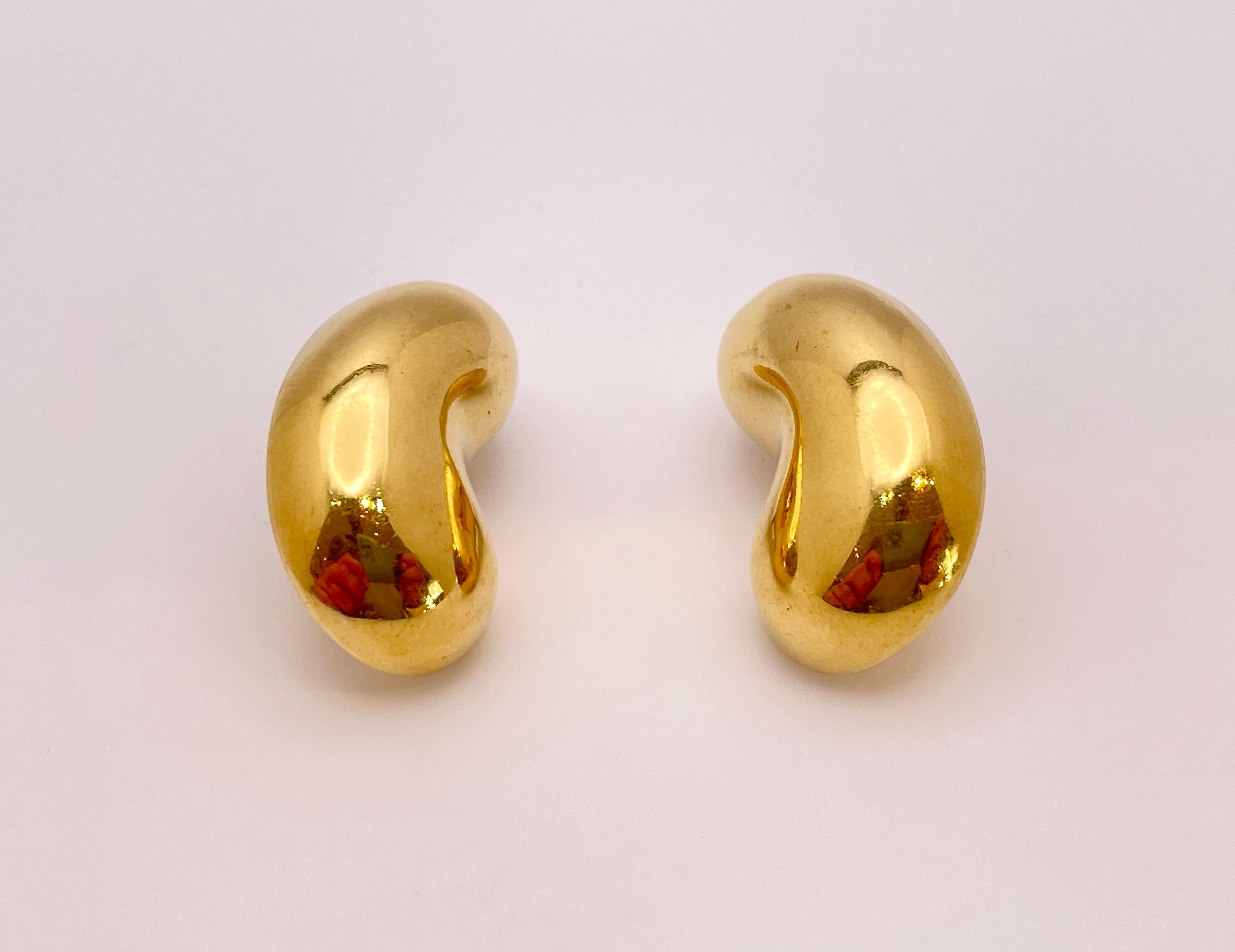 A magnificent pair of 18K yellow gold bean design earrings. These unique earrings feature a lever back post backing. Their gross weight is 14.90 grams and they both measure approximately 1.20 x 0.50 x 0.25 inches. Embrace effortless elegance with