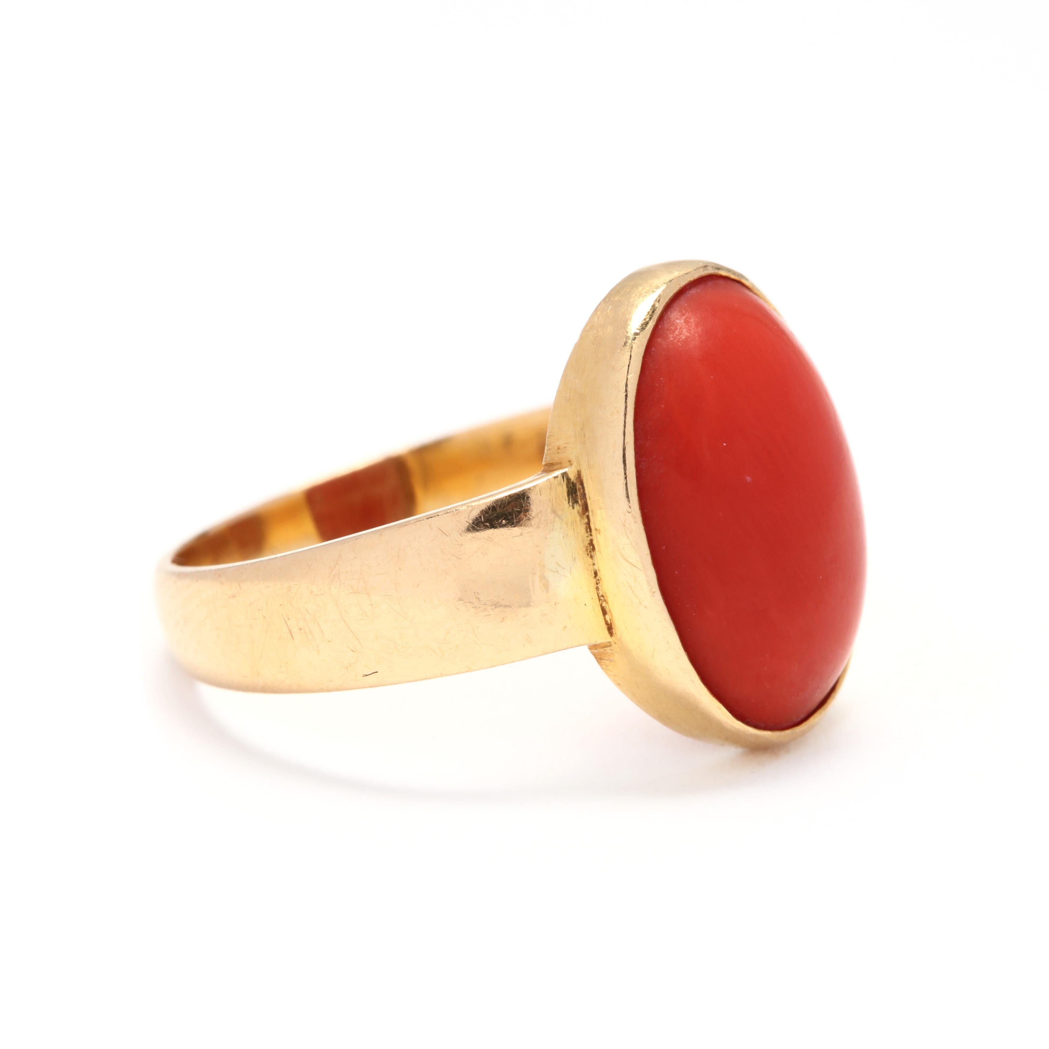 An 18 karat yellow gold and bezel set coral solitaire ring. An oval, cabochon coral center stone, bezel set on a wide slightly tapered shank.

Stone:
- coral, 1 stone
- oval, cabochon
- 13.5 x 9.75 x 4.4 mm

Ring Size 6.75

Width: 14.8 mm

2.96