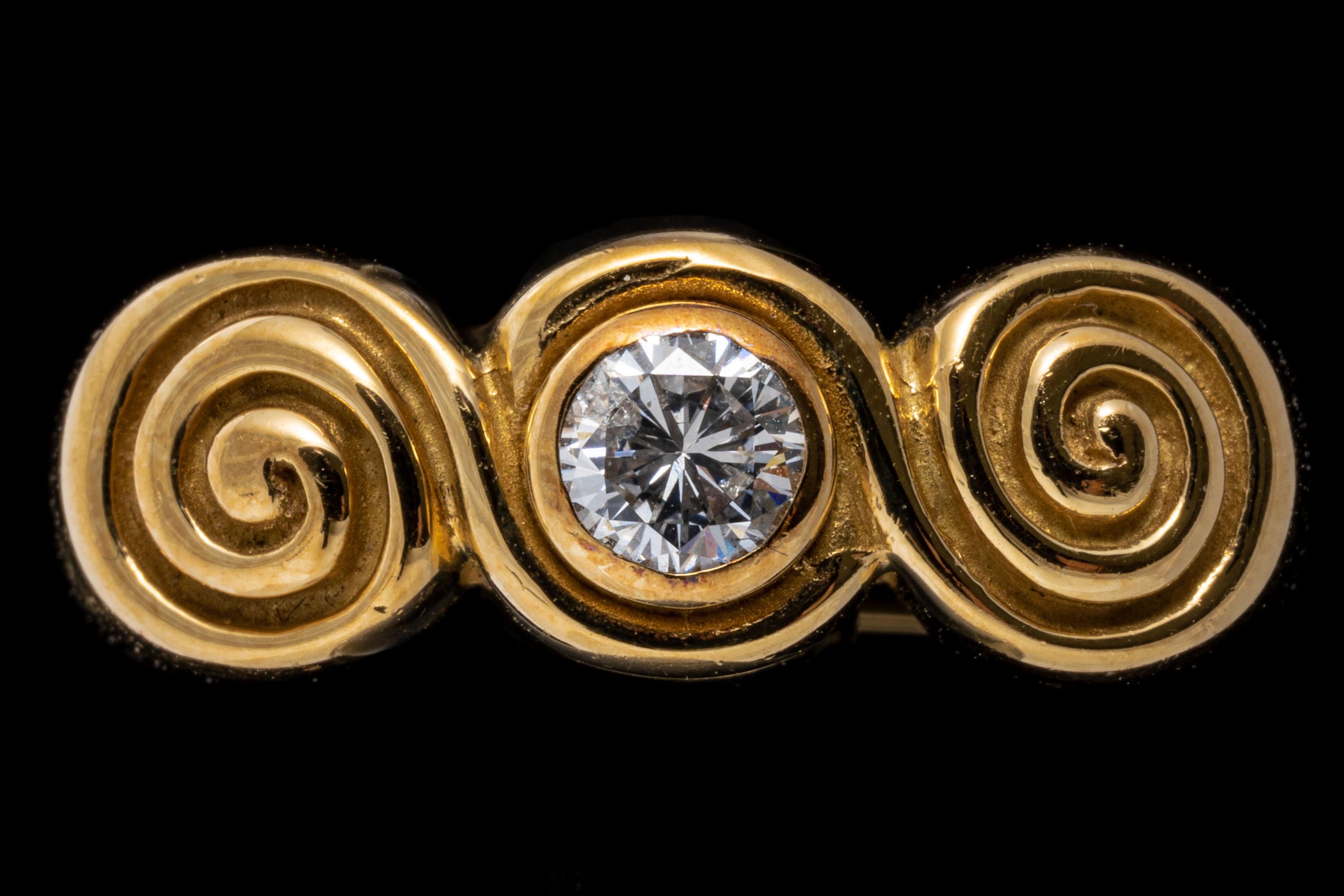 ring aus 18k Gelbgold. Dieser hübsche und einzigartige Ring aus Gelbgold zeigt in der Mitte einen runden Diamanten im Brillantschliff, ca. 0,26 CTS, der in der Lünette gefasst ist. Er wird von zwei gewirbelten Schnecken flankiert und ist mit