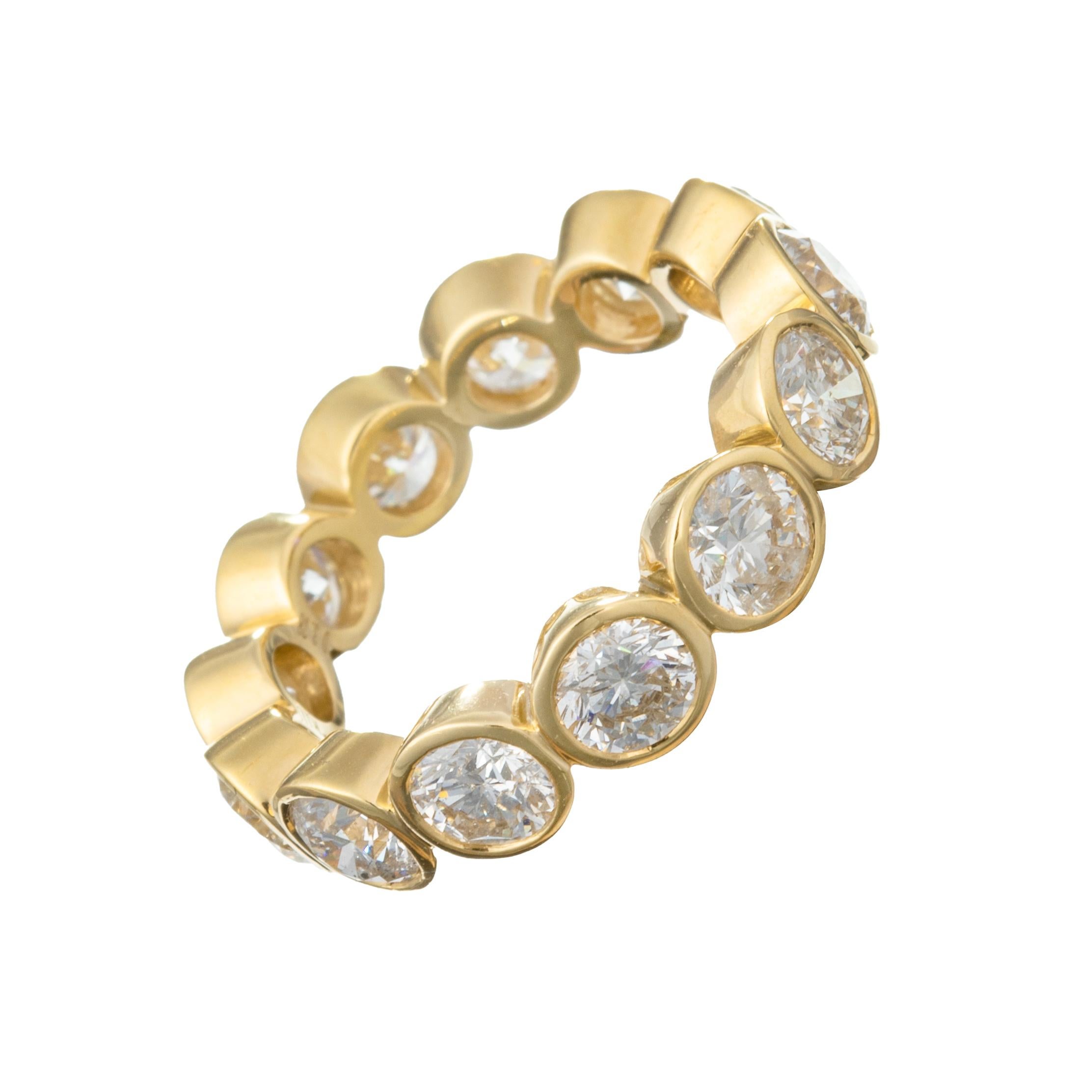Eternity-style band ring handcrafted in high-polished 18k yellow gold.  Finely crafted with diamonds surrounding the entire band, each individually bezel-set with a gold rim around each diamond.  Thirteen diamonds weighing 3.78 total carats.  Size