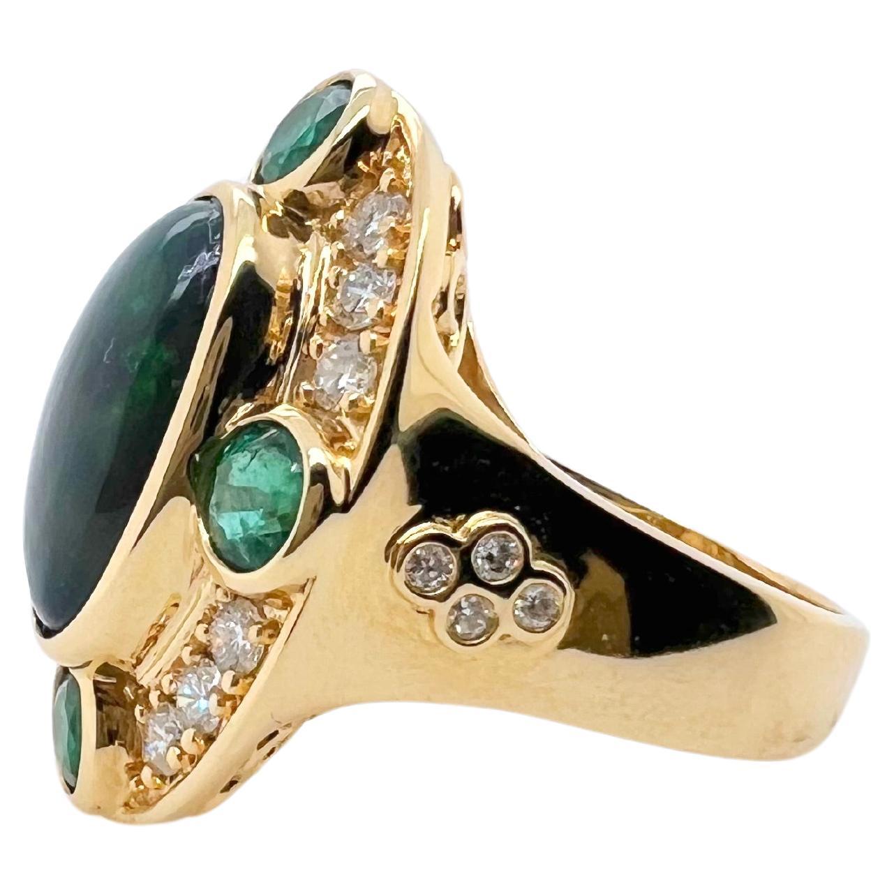This gorgeous black Ethiopian is bezel set in this handmade 18k yellow gold mounting. There are 4 round green emeralds bezel set that sits on a bed of round brilliant diamonds. The 4 bezel set diamonds on each side of the shank give character to