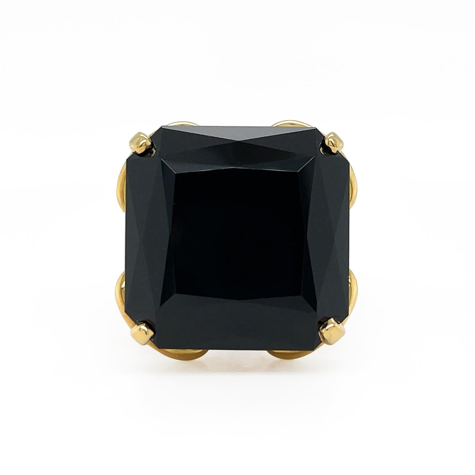Black jade is invigorated by gold for this ring. A facetted cushion carved black jade allows the gem to glimmer. 18k yellow gold prongs secure each corner, while strands of the metal interlace and loop for a unique pattern and multi-split band. The